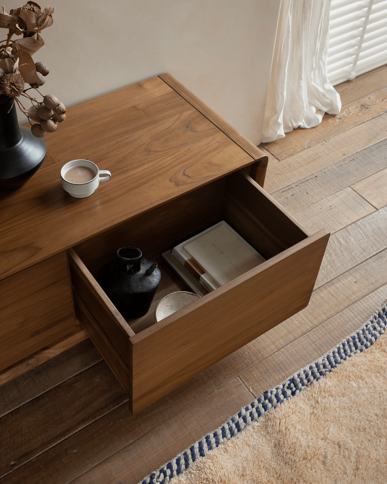 NO.34 Media Console, open drawer revealing contents; wooden cabinet, books, and coffee cup