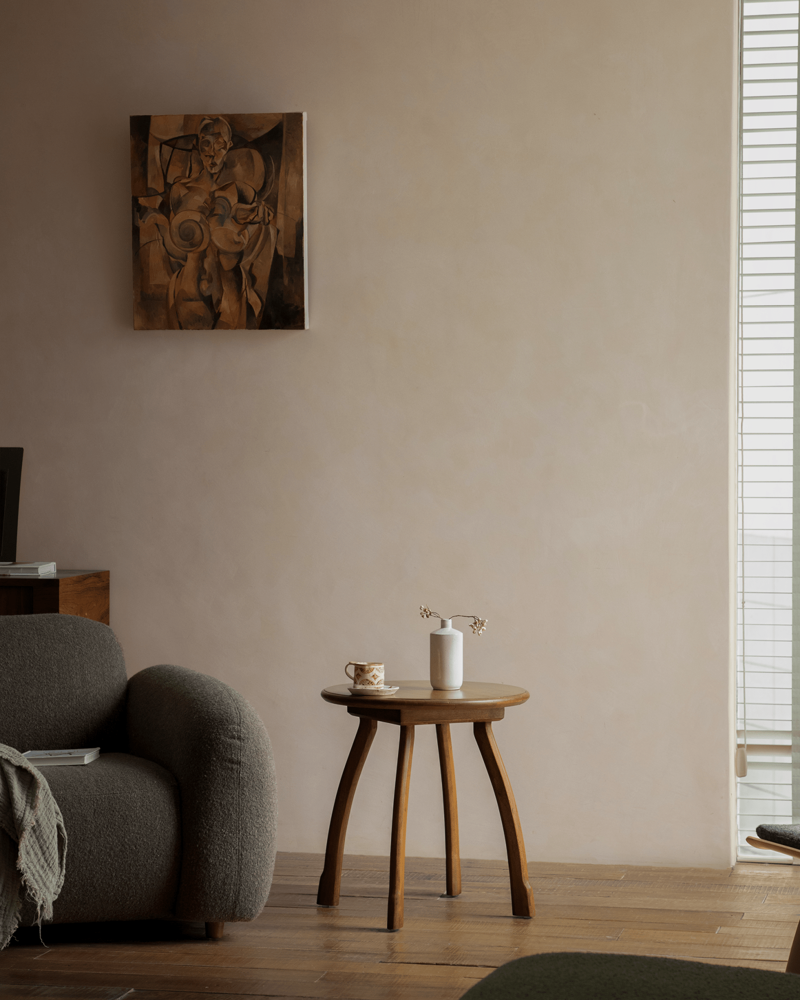 Ele Round Side Table in a vintage interior. Phoebe wood table with octopus legs next to grey armchair.