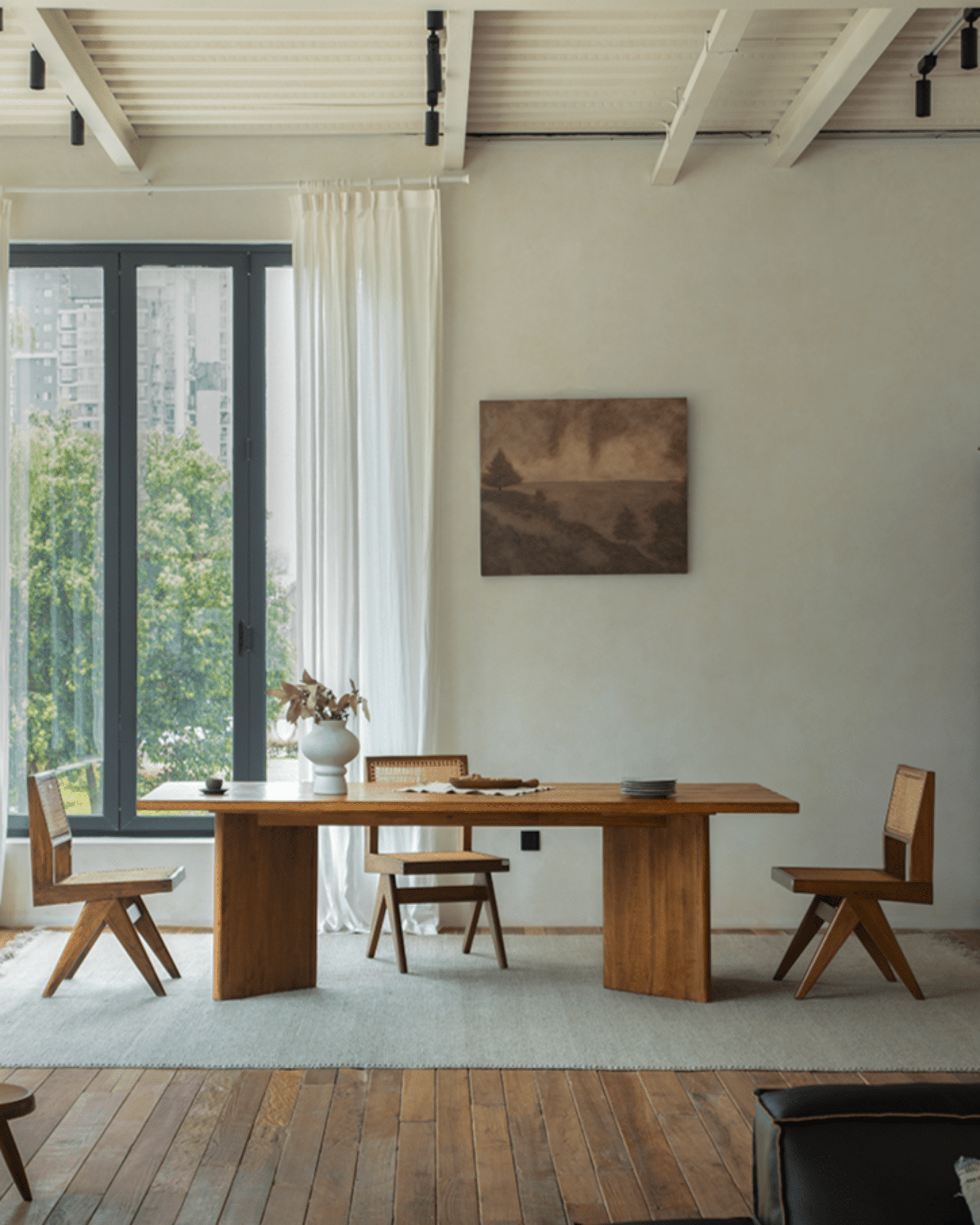 Zephyr Dining Table in a bright, minimalist dining room, natural wood with woven chairs