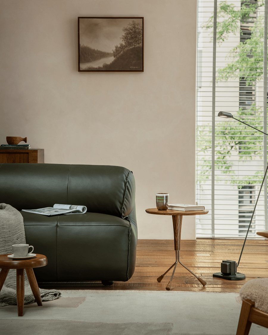 Larsson Side Table showcased in a modern living room setting, featuring ebony wood, Aged Brass accents, and a tripod base.