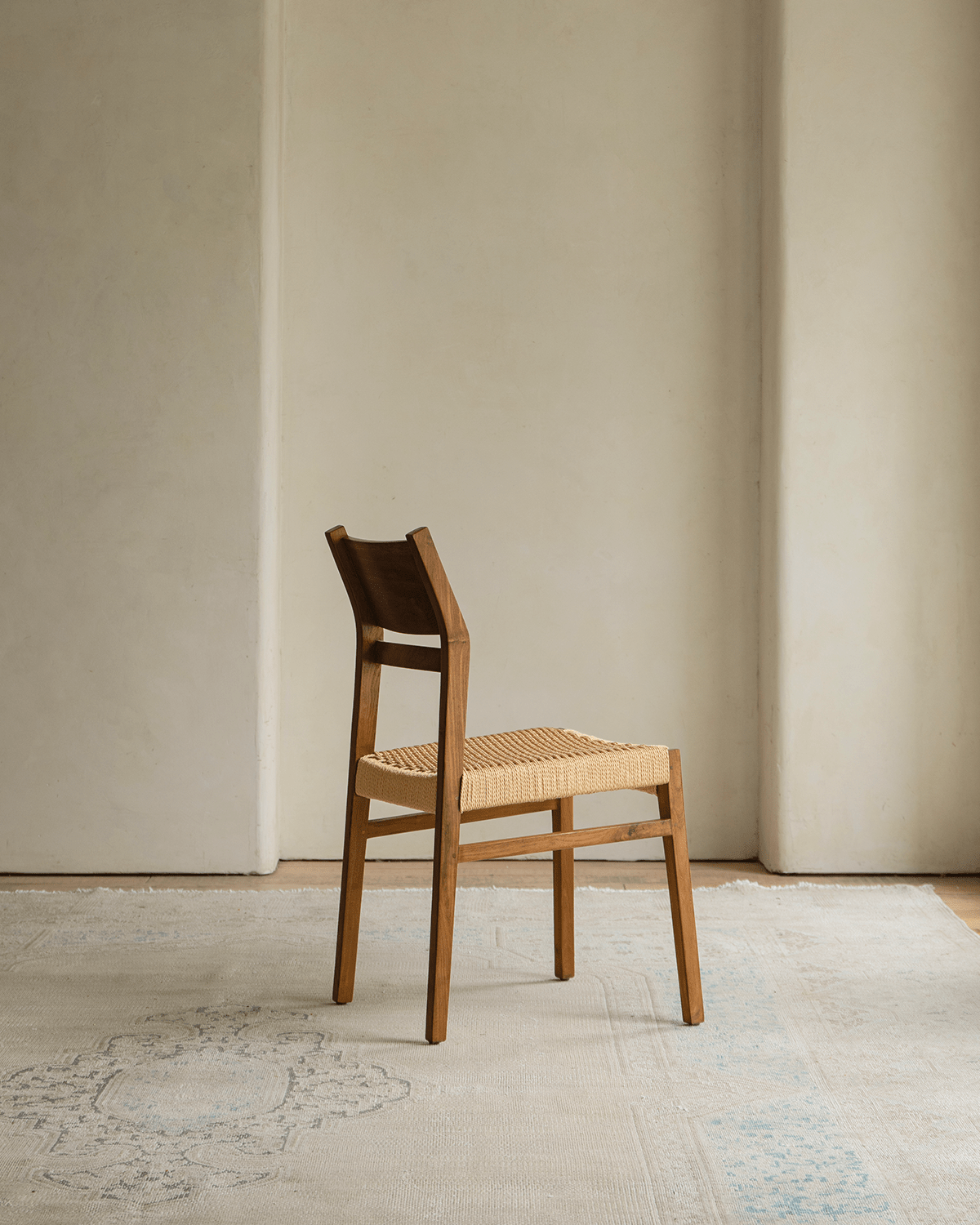 Beam Chair with teak wood frame and woven seat, showcasing minimalist design and natural warmth