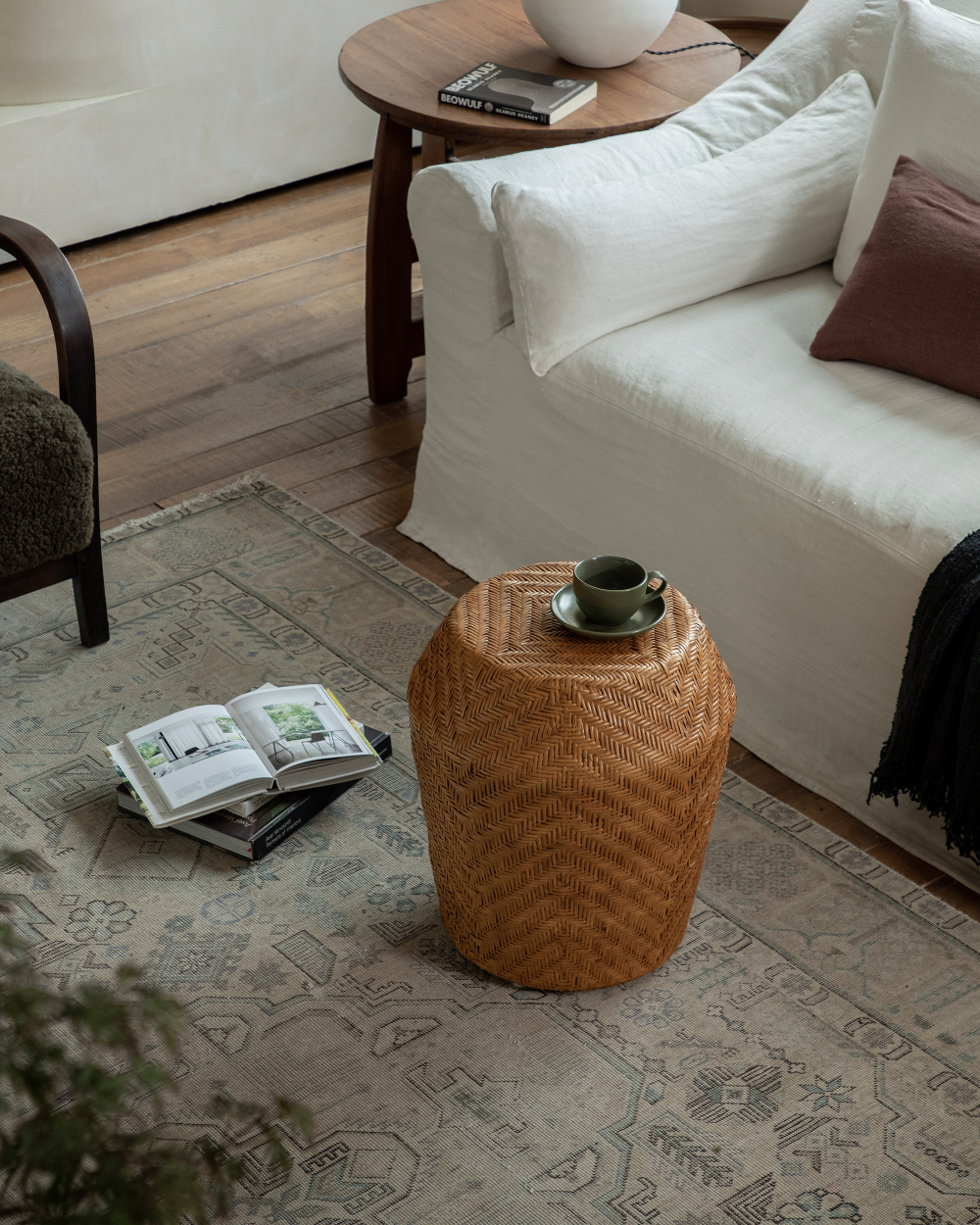 Drum Rattan Side Table: Handwoven rattan with herringbone weave, holding a cup.