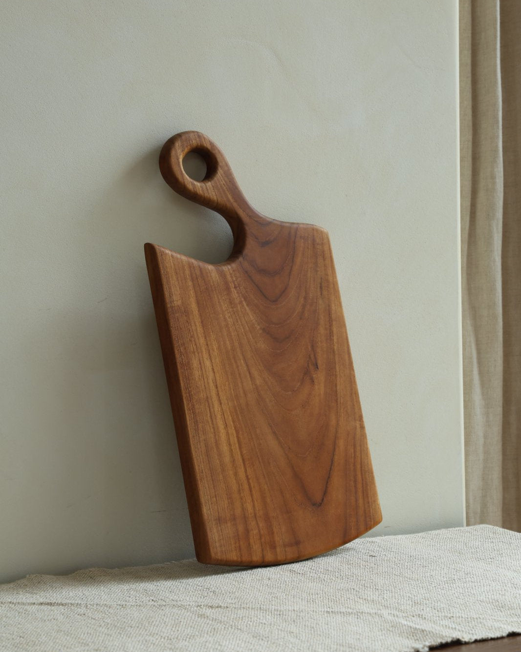 Handcrafted teak wood cutting board with curved handle and hanging hole