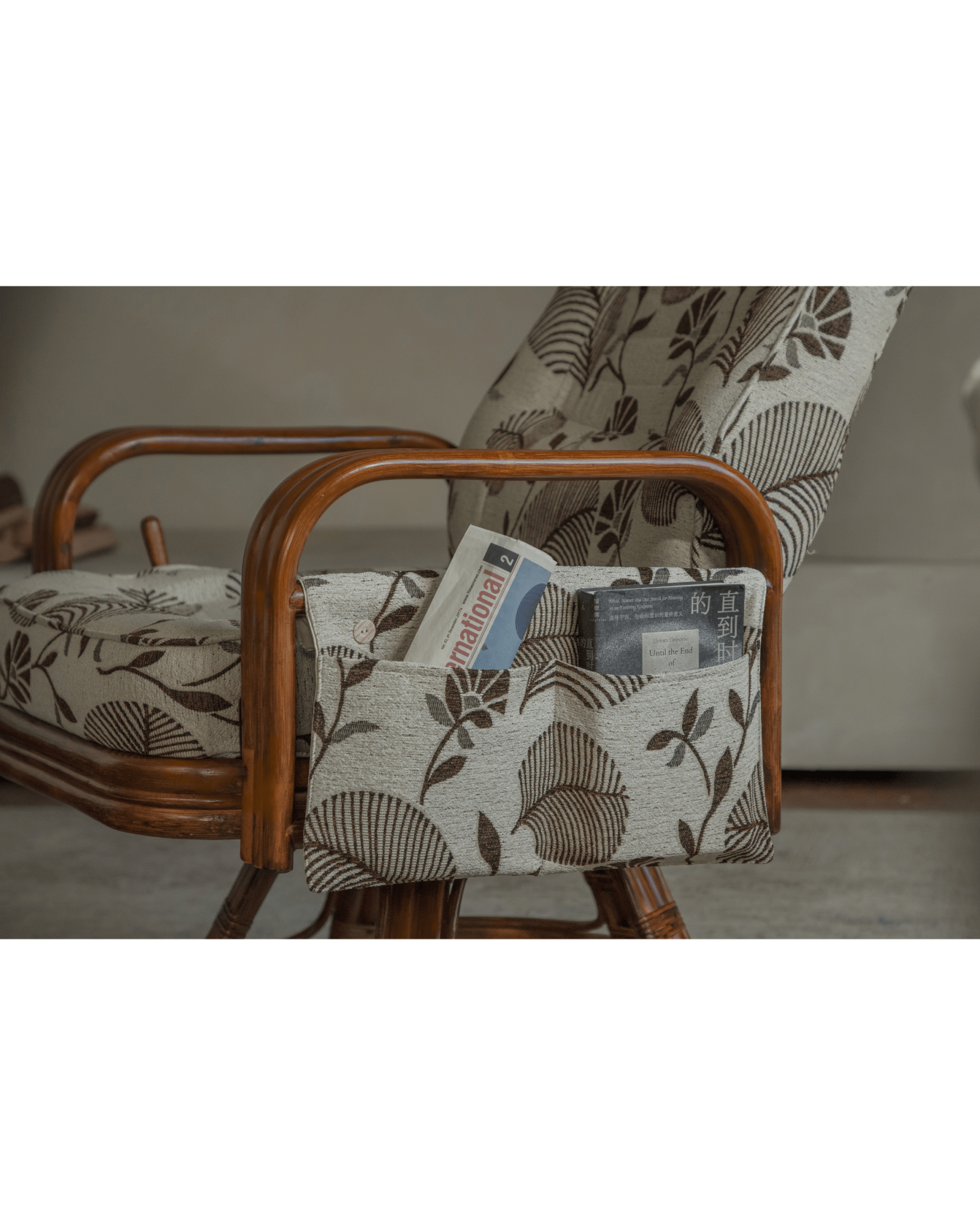 Willow rattan chair with floral pocket, Indonesian rattan, featuring "International" newspaper and book.