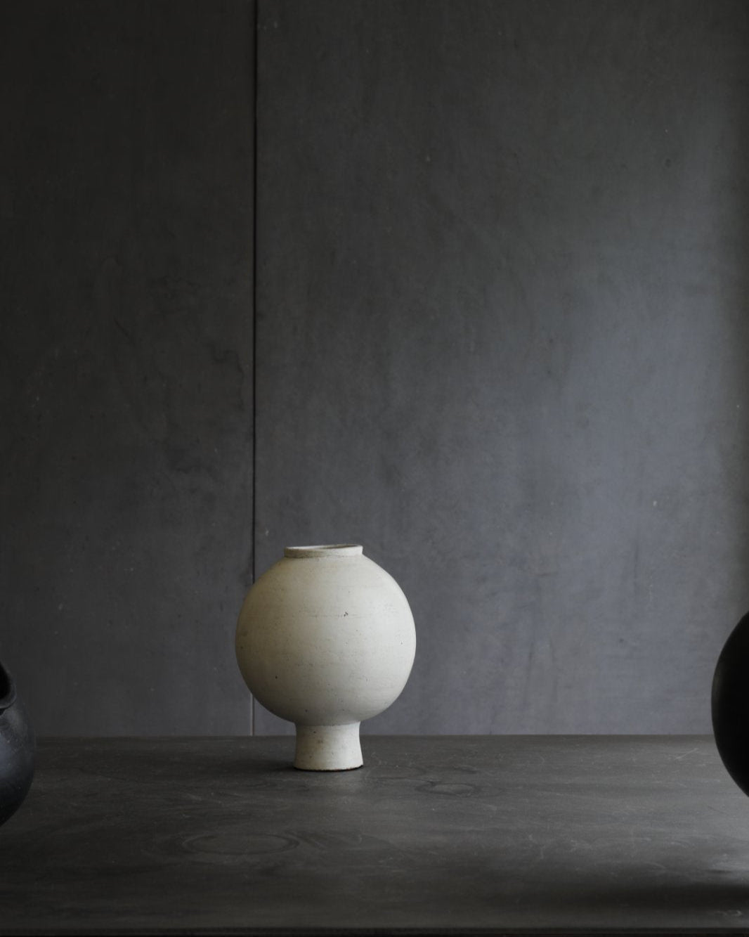Off-white ceramic sphere vase with short base. Minimalist design for home decor.