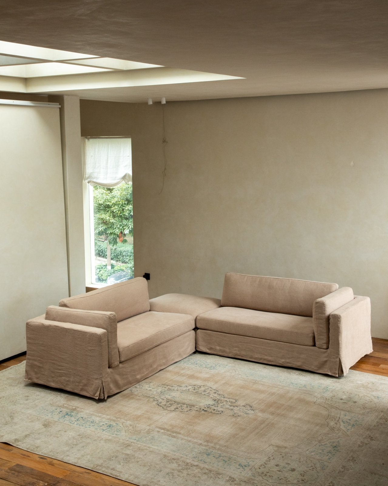Beige linen skirt sectional sofa in modern living room with modular design and rug