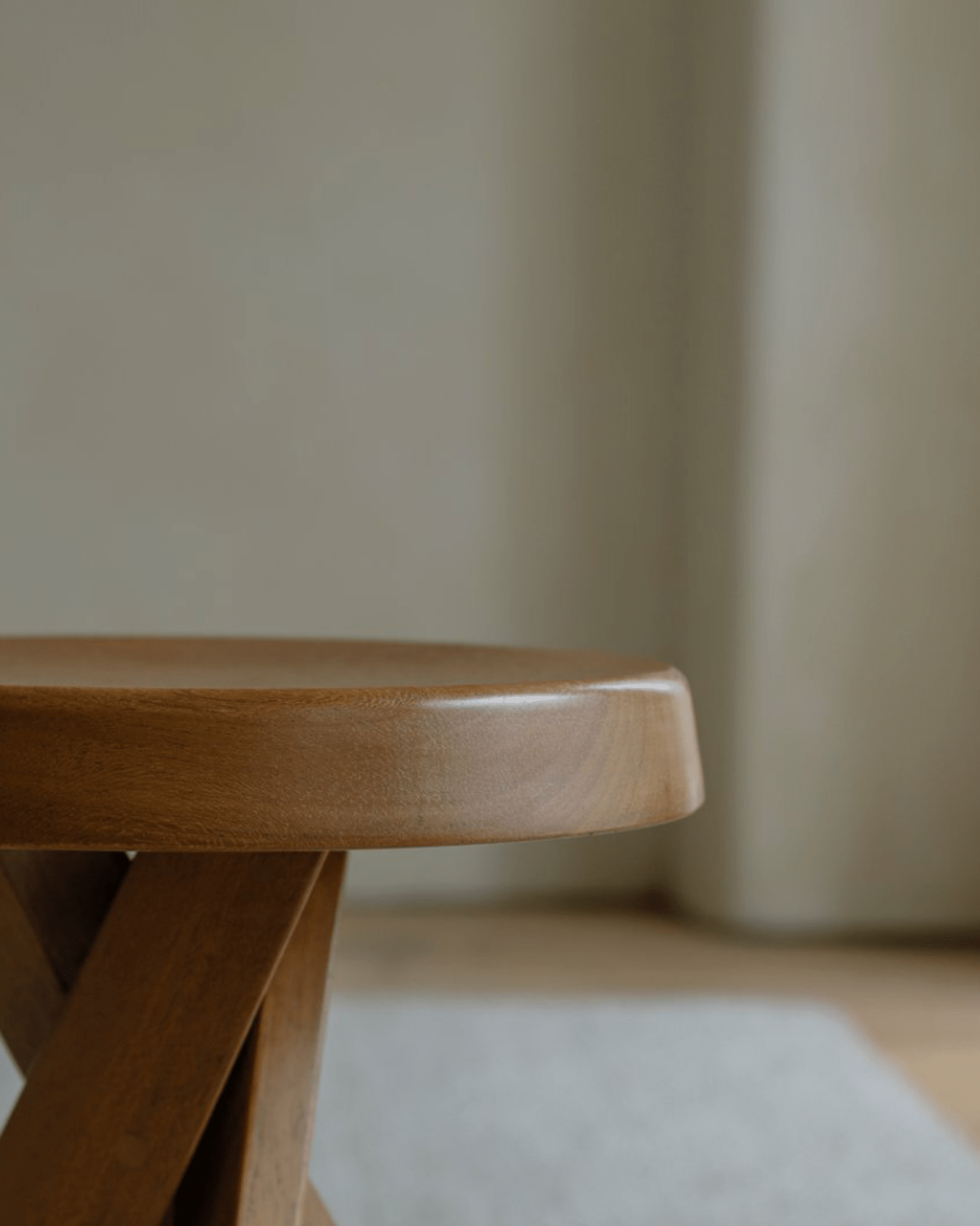 Close-up of a natural wood French stool, showcasing the smooth finish and round seat for modern home decor