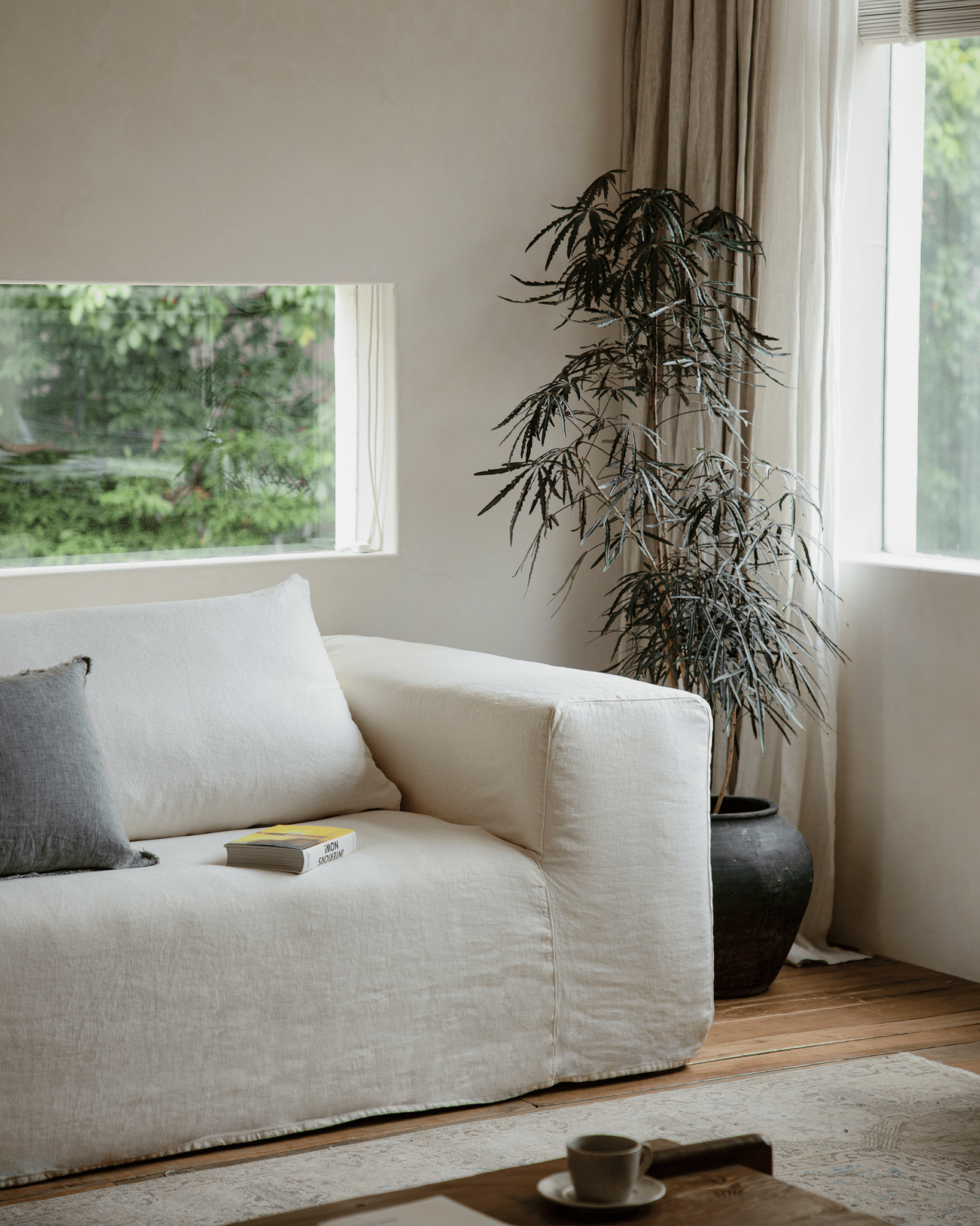 Doma sectional sofa in white linen with wide armrests in a bright living room. Includes book "INTERIORS NOW!"