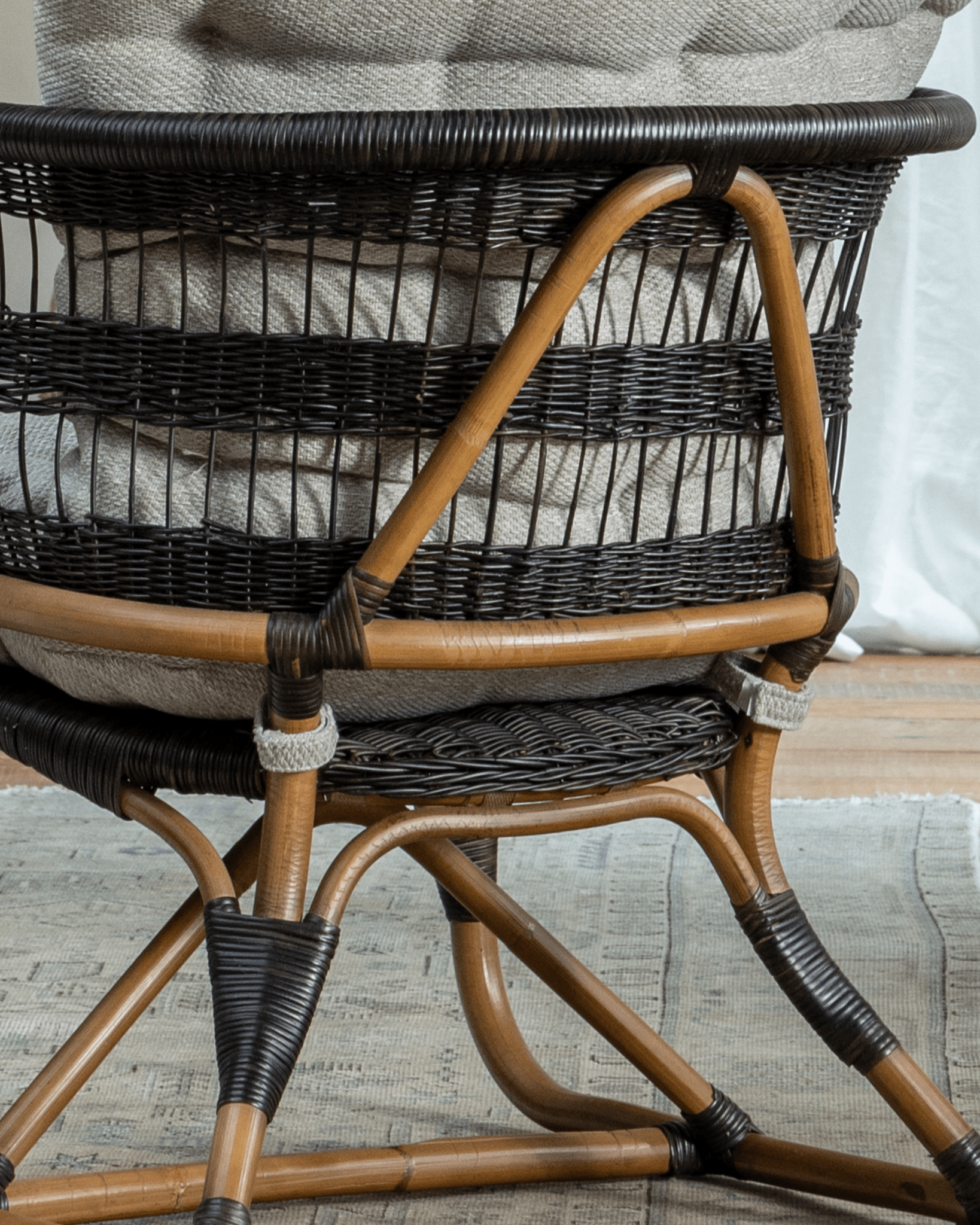 Helian Rattan Chair detail: natural rattan frame with black accents, gray cushion, handcrafted design