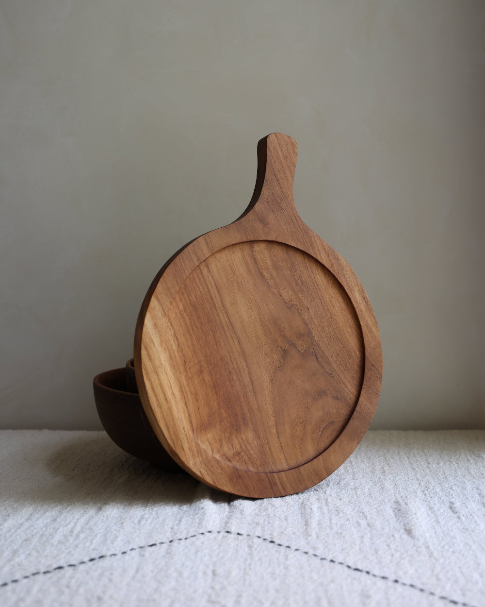 Round teak wood butcher block with integrated handle for serving