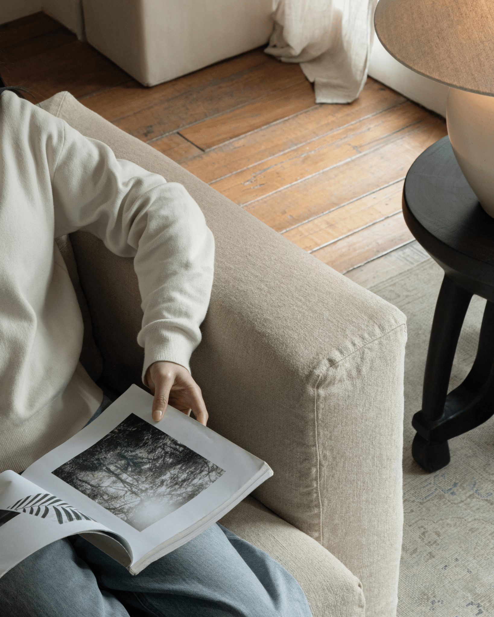 Nola Sofa in Natural Linen, comfortable living setting with a book. Featuring breathable linen fabric and stylish design.