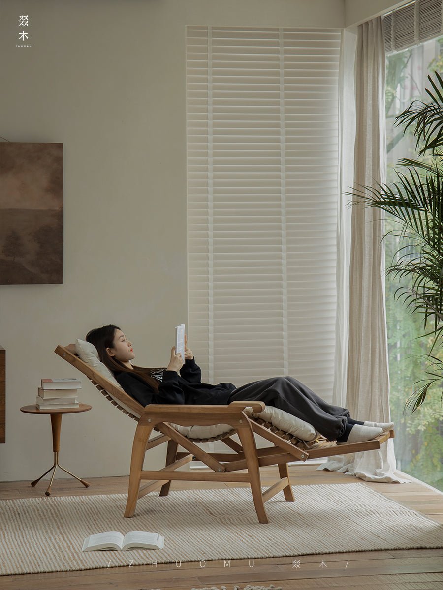 Woman relaxing on a teak wood Roller Chaise Lounge Chair indoors; perfect for lying down with full-body support