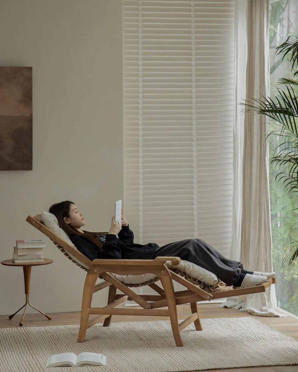 Woman relaxing on a teak wood Roller Chaise Lounge Chair indoors; perfect for lying down with full-body support