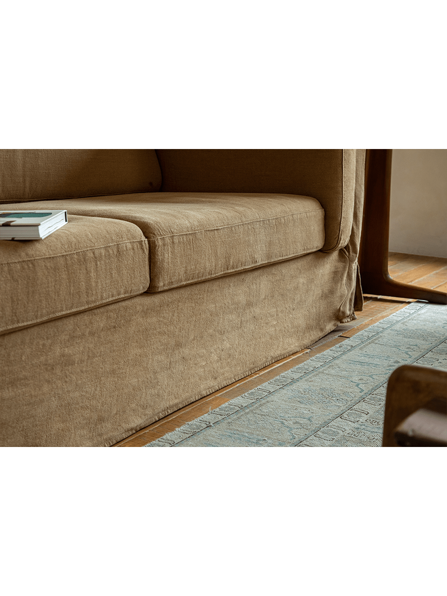 Tan linen Skirt Sofa detail. Modern design with breathable fabric and skirt. Ideal for a comfortable and peaceful space.