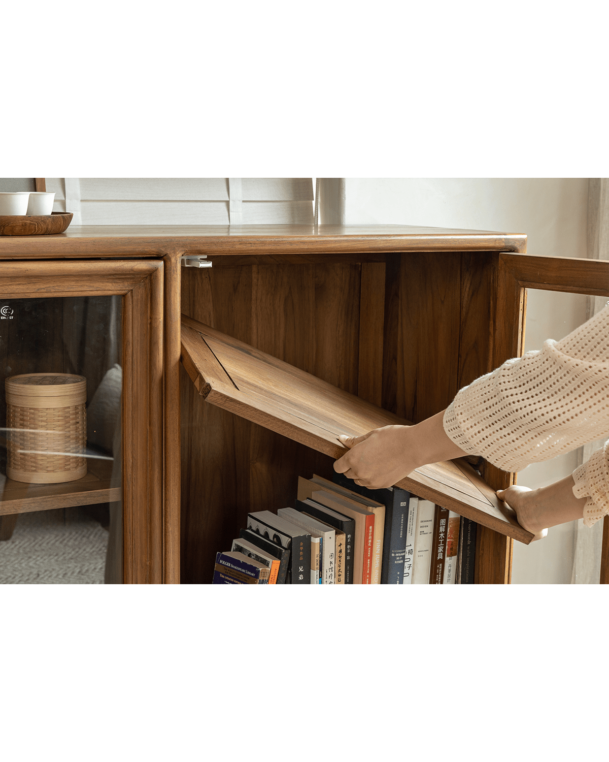 Teak Stilt Cabinet, person opening shelf, glass doors showcasing storage, elegant dining room display solution.