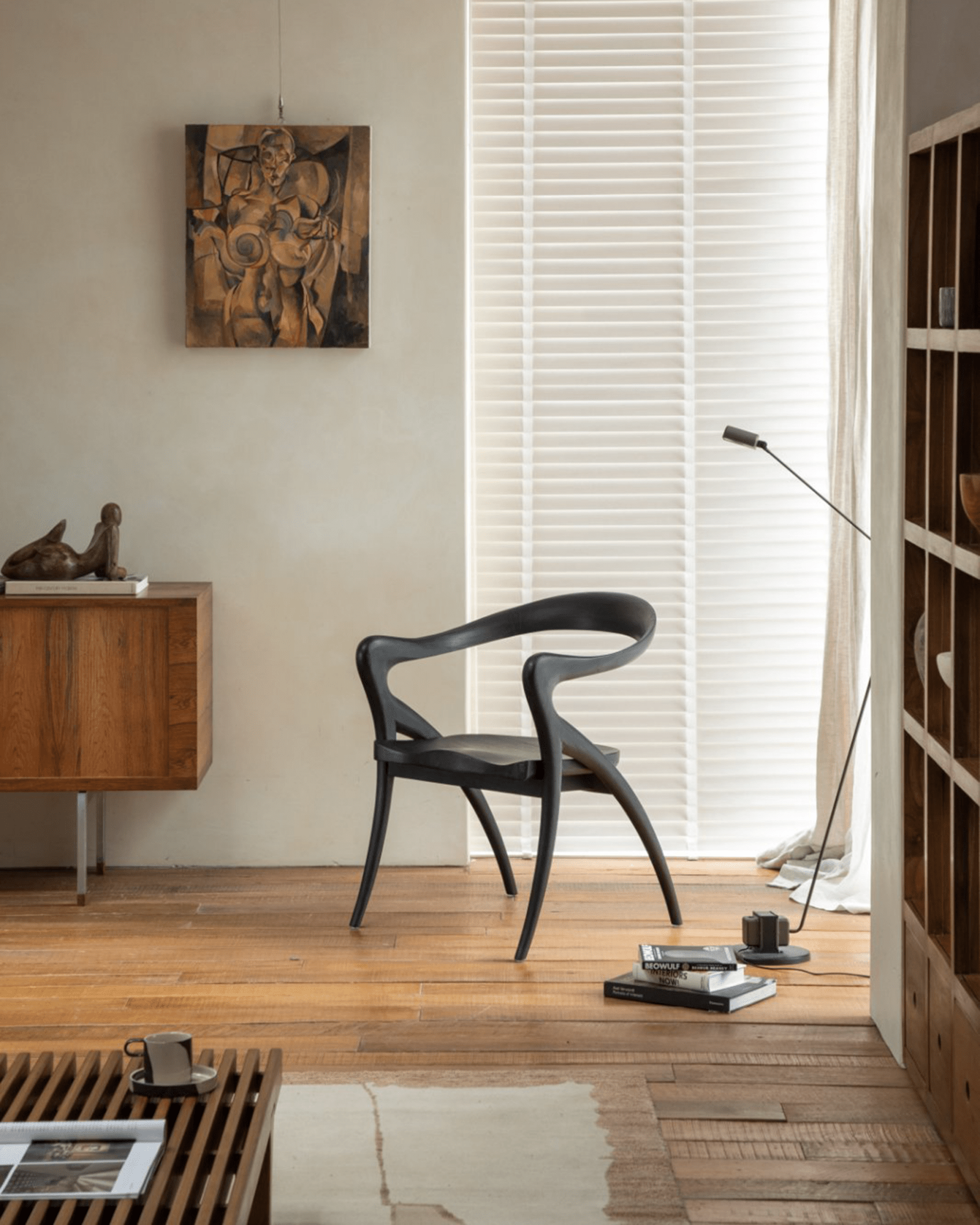 Black Olivia chair in modern interior. Curved backrest, contoured seat, and tapered legs. Modern teak wood design