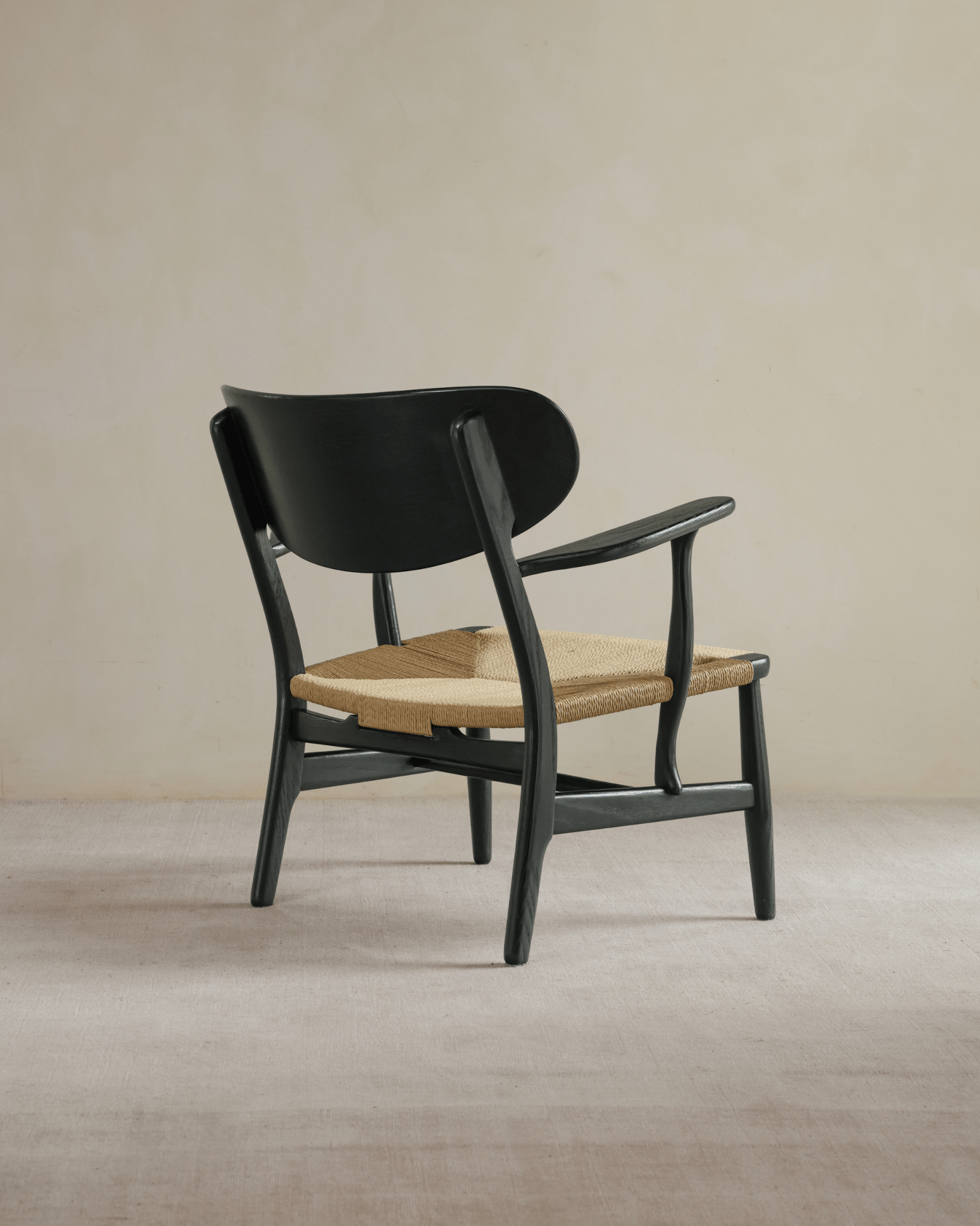 CH22 Lounge Chair, black frame and backrest, woven paper cord seat, Danish design icon for modern interiors