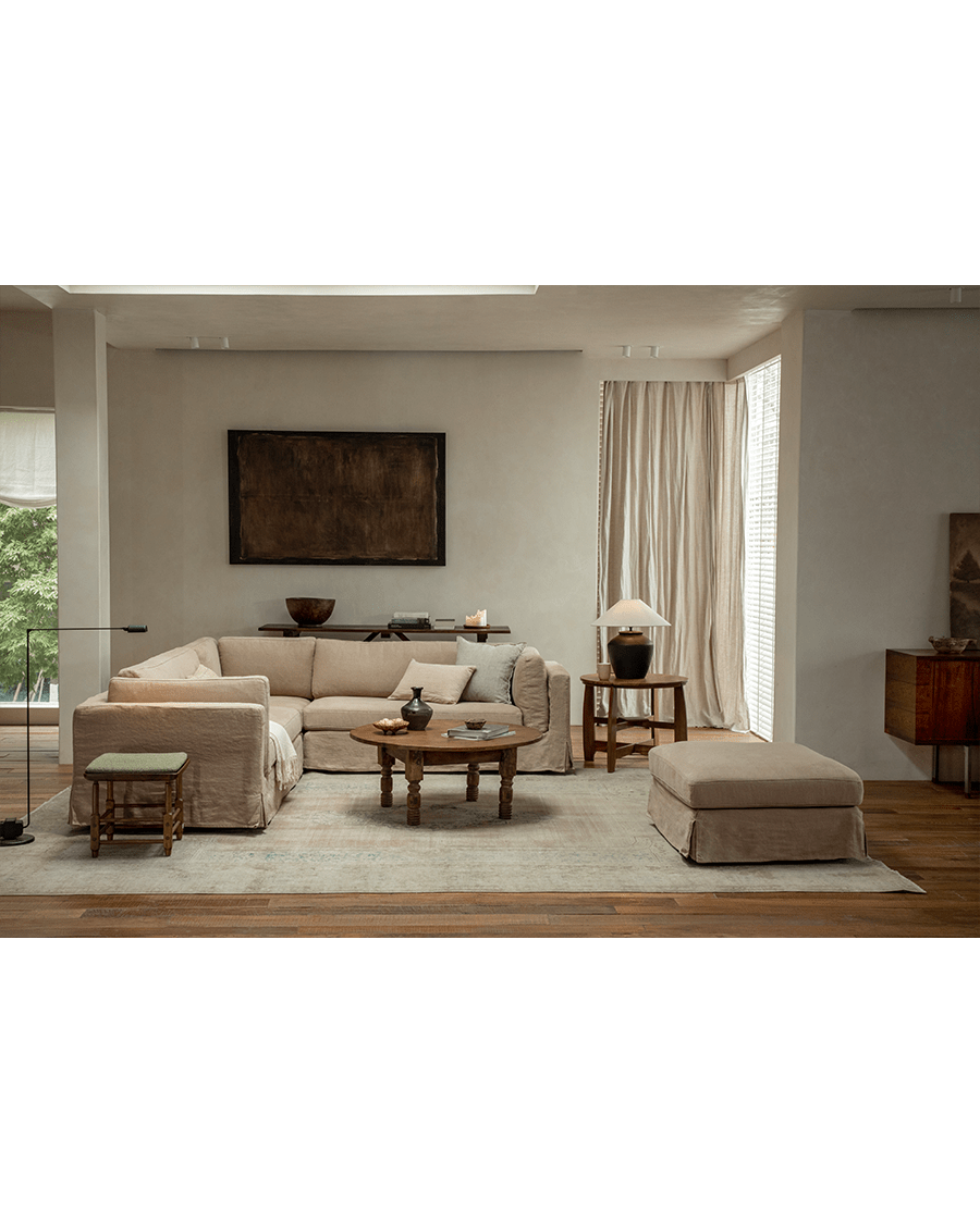 Skirt sectional sofa in natural linen upholstery with skirted design and ottoman.