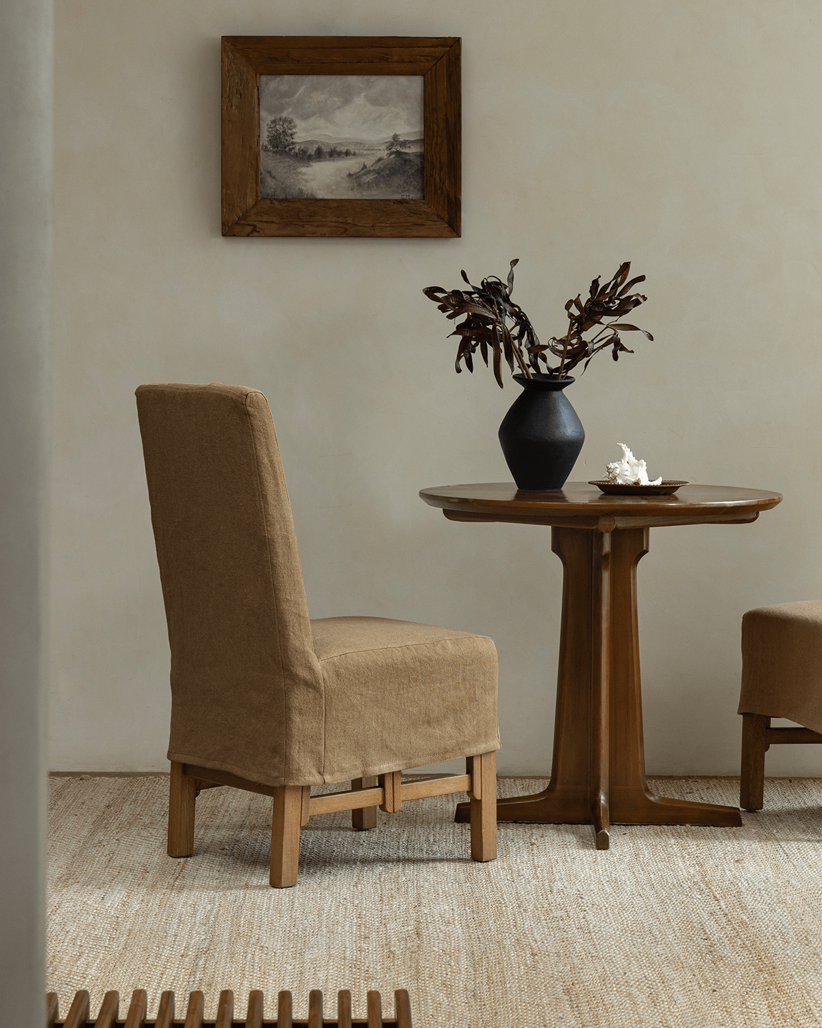 Feast Dining Chair in tan linen slipcover beside a wood table, modern interior design, neutral tones