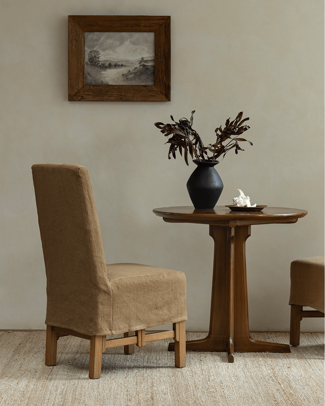 Feast Dining Chair in tan linen slipcover beside a wood table, modern interior design, neutral tones