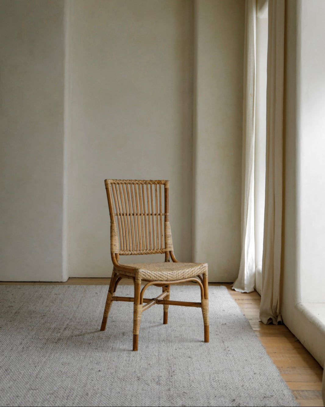 Axis Chair: Indonesian rattan armchair with woven seat and slatted back on grey rug
