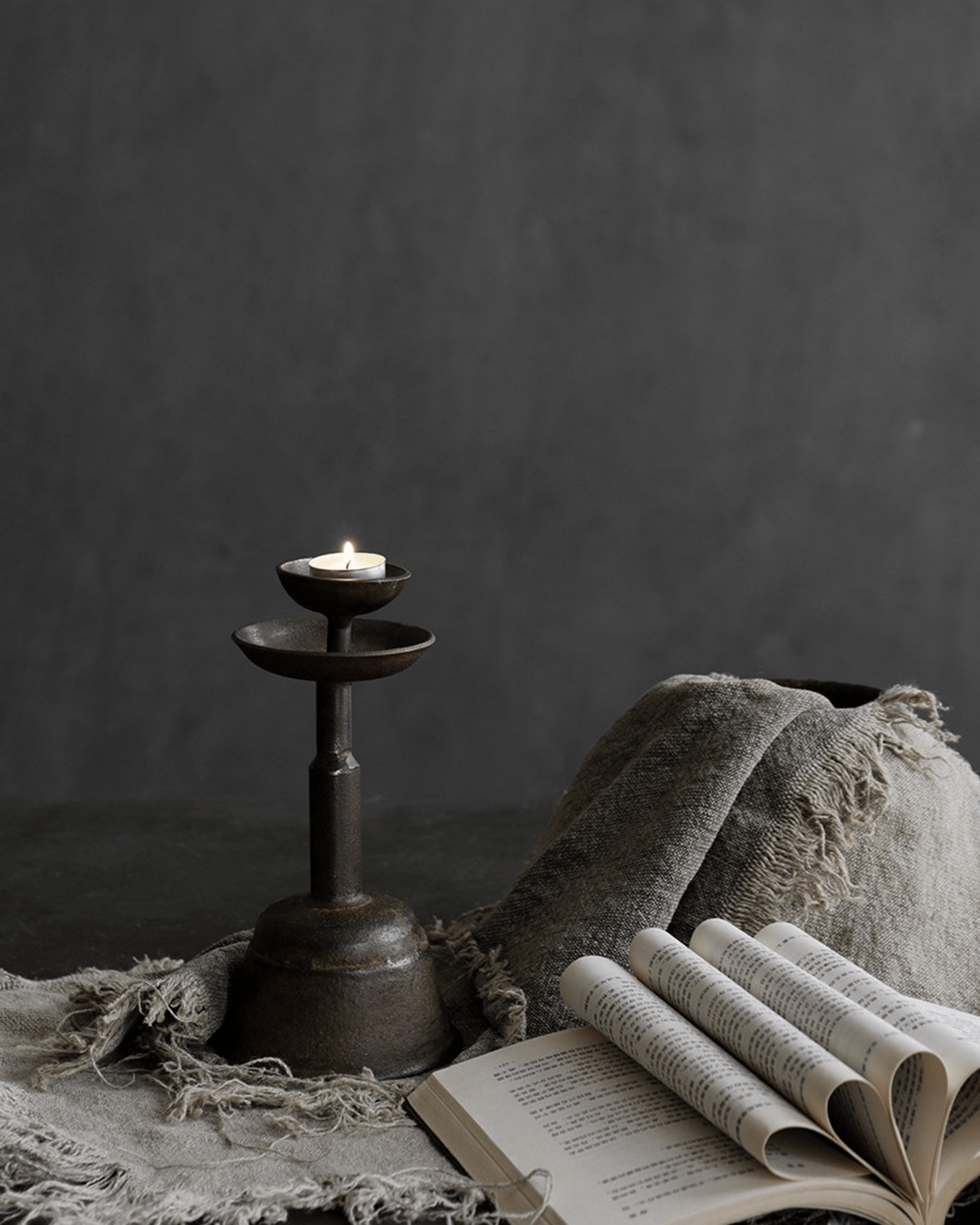 Rustic iron candle holder with lit candle and book, cozy home décor, warm ambiance