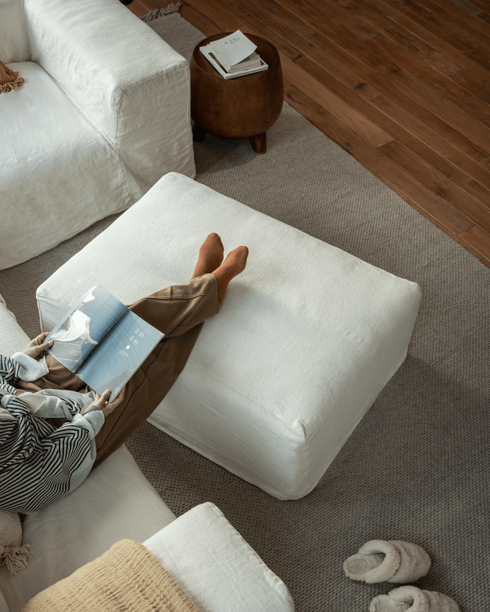 Doma sectional sofa with white linen ottoman, reading book in relaxed living space