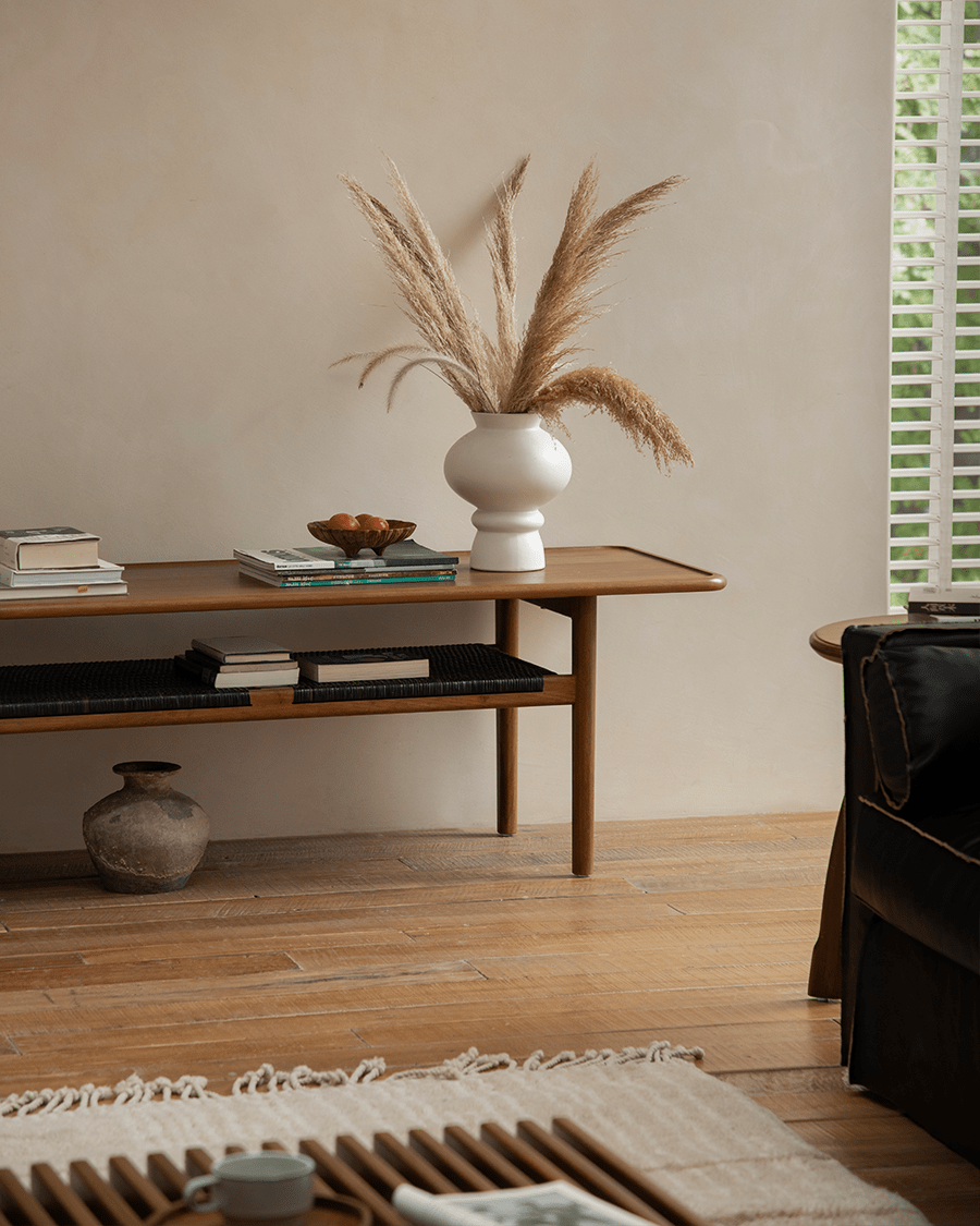Hans Accent Table in a modern living room, wooden coffee table with woven shelf, minimalist design.