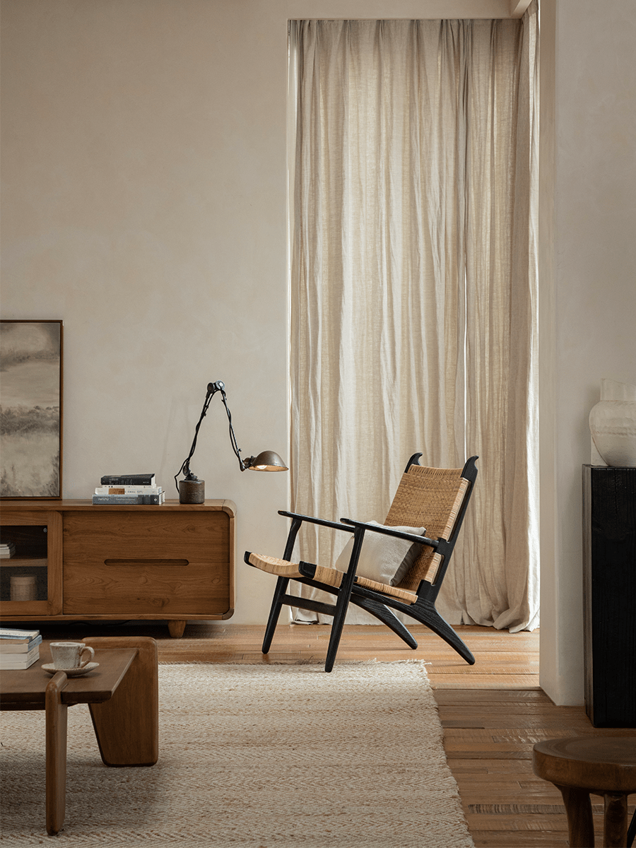 Horn Lounge Chair in a cozy interior setting, featuring a black oak frame and natural rattan seat.