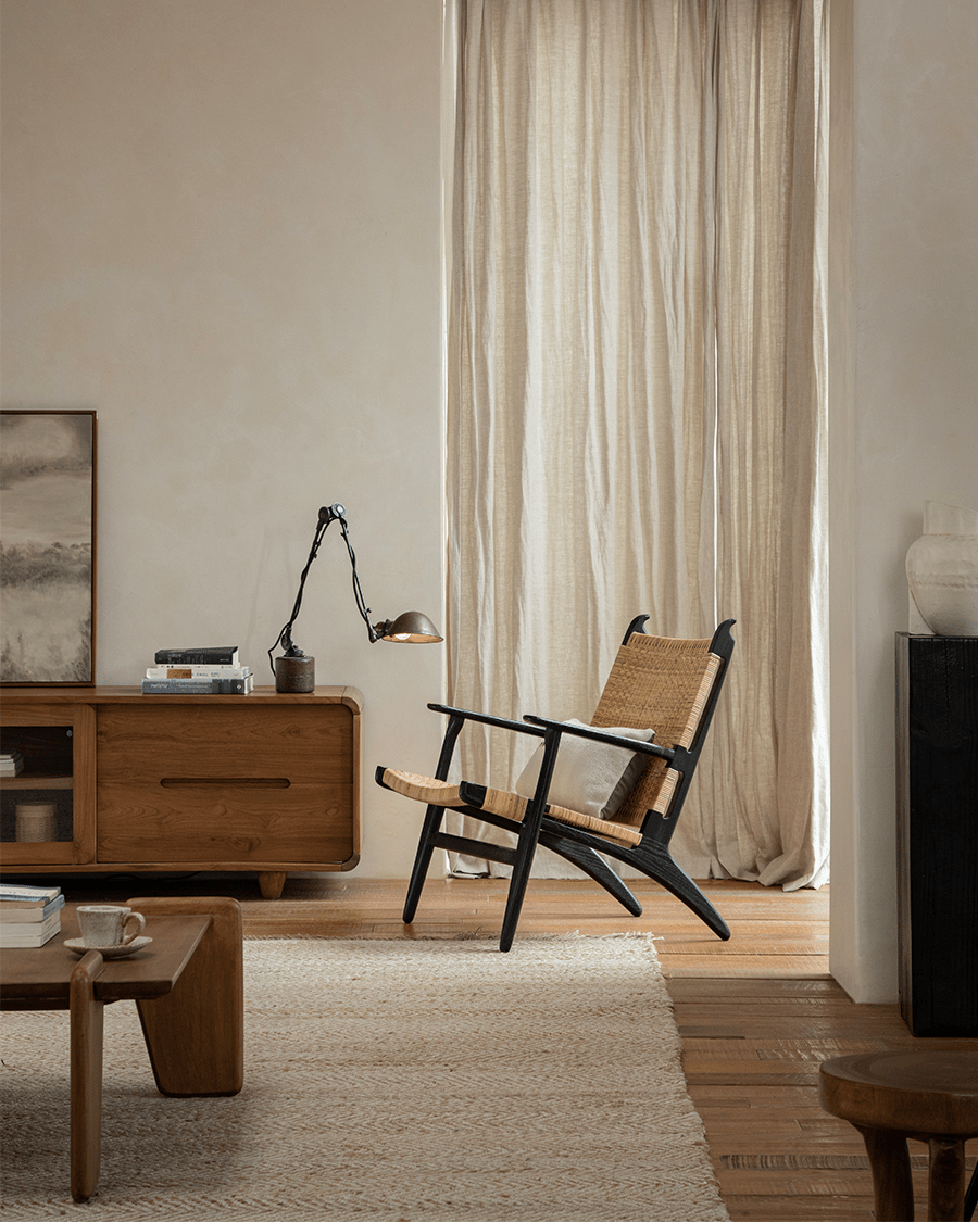 Horn Lounge Chair in a cozy interior setting, featuring a black oak frame and natural rattan seat.