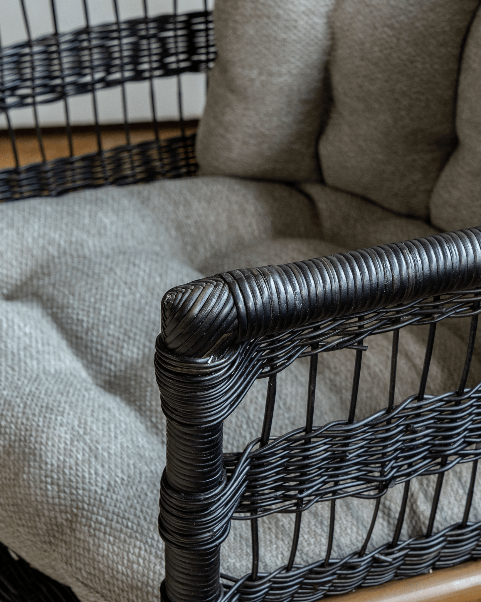 Helian Rattan Chair detail: black rattan frame, gray silk cushion, and handcrafted design
