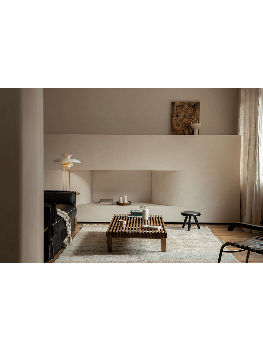 ZM Daybed Coffee Table in teak wood, minimalist design, modern living room setting with leather sofa and art.