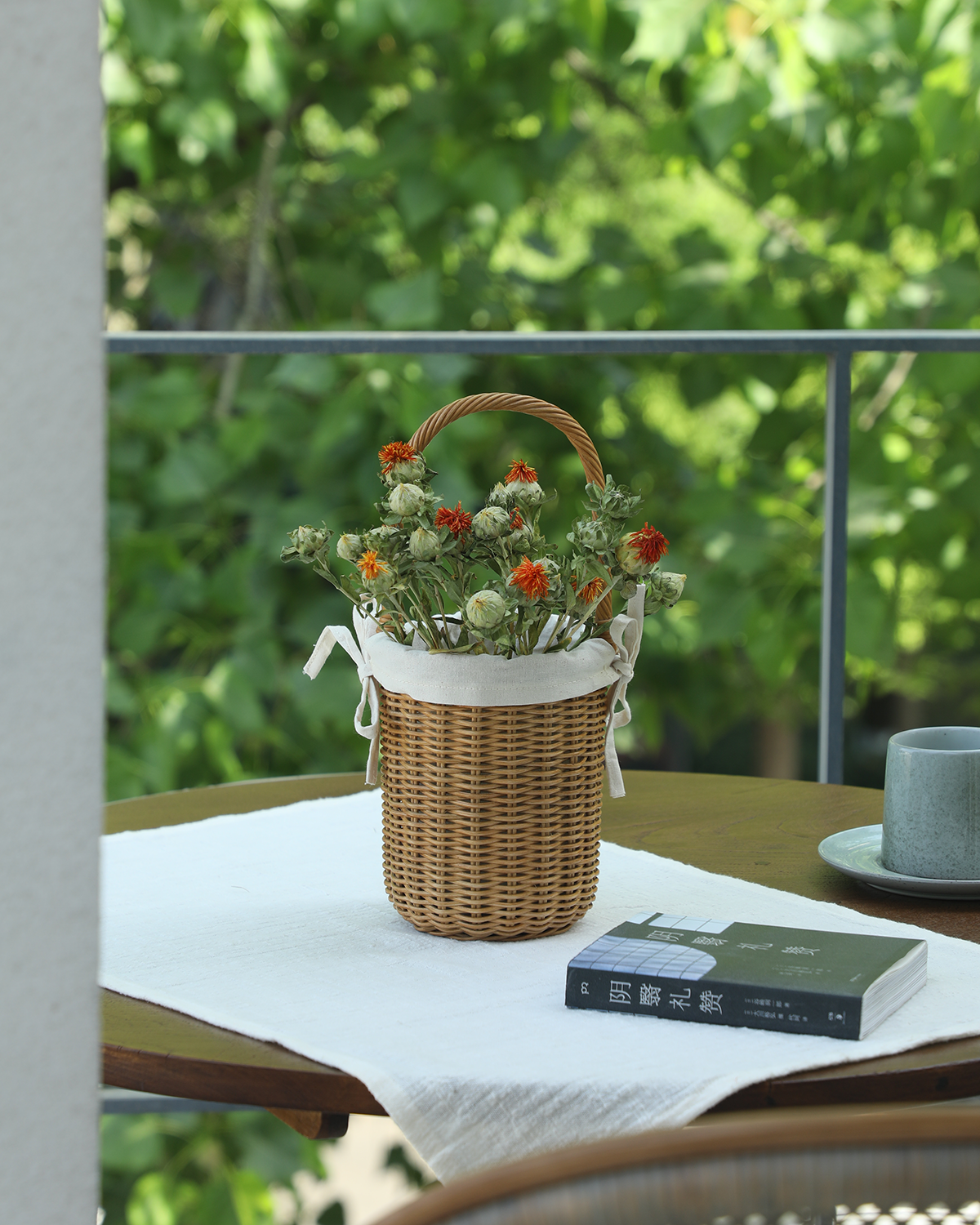 Natural hand-woven rattan Iris Basket with arched handle, white cotton lining, and dried flowers.
