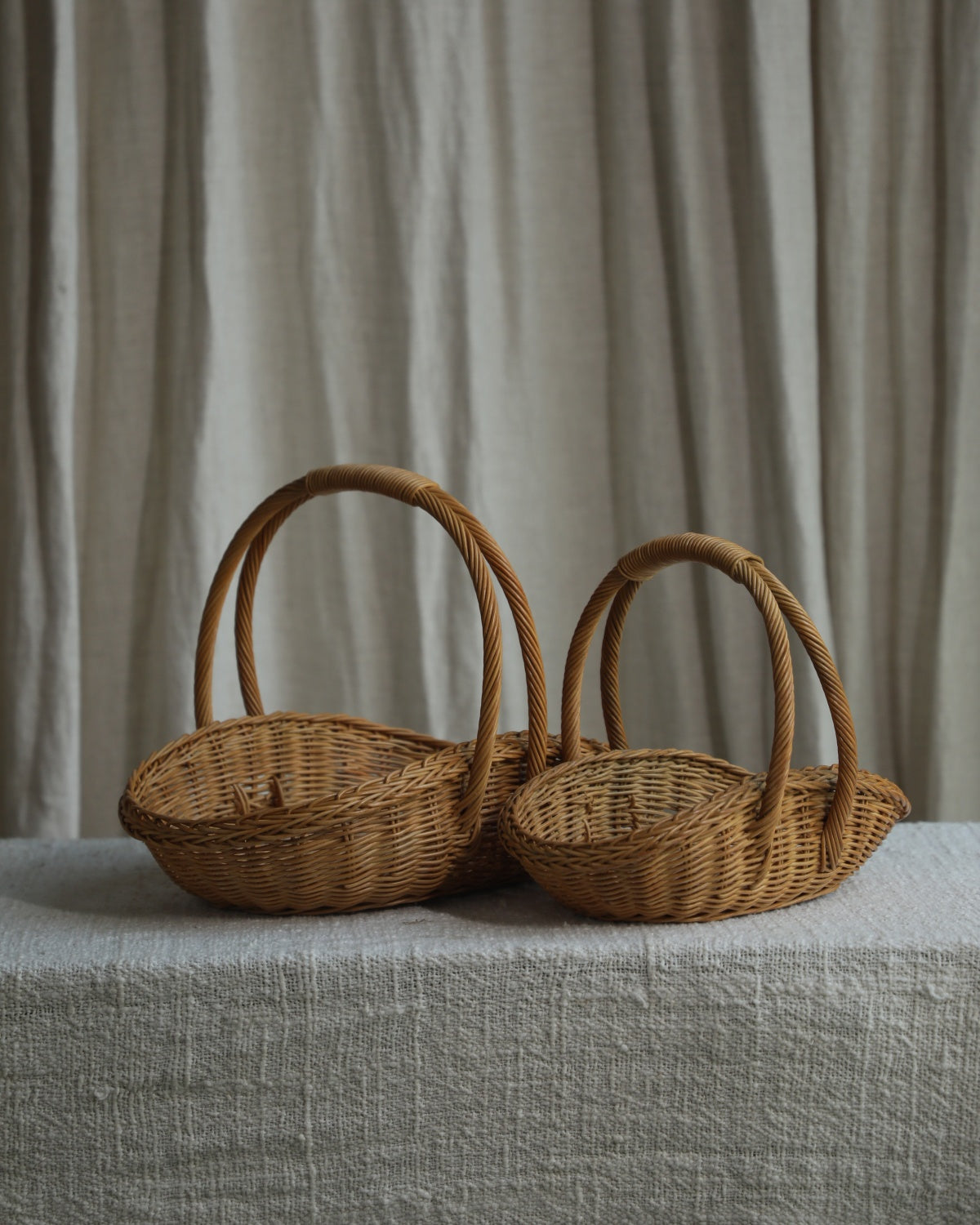 Two natural rattan Venus gathering baskets with tall handles, small and large sizes