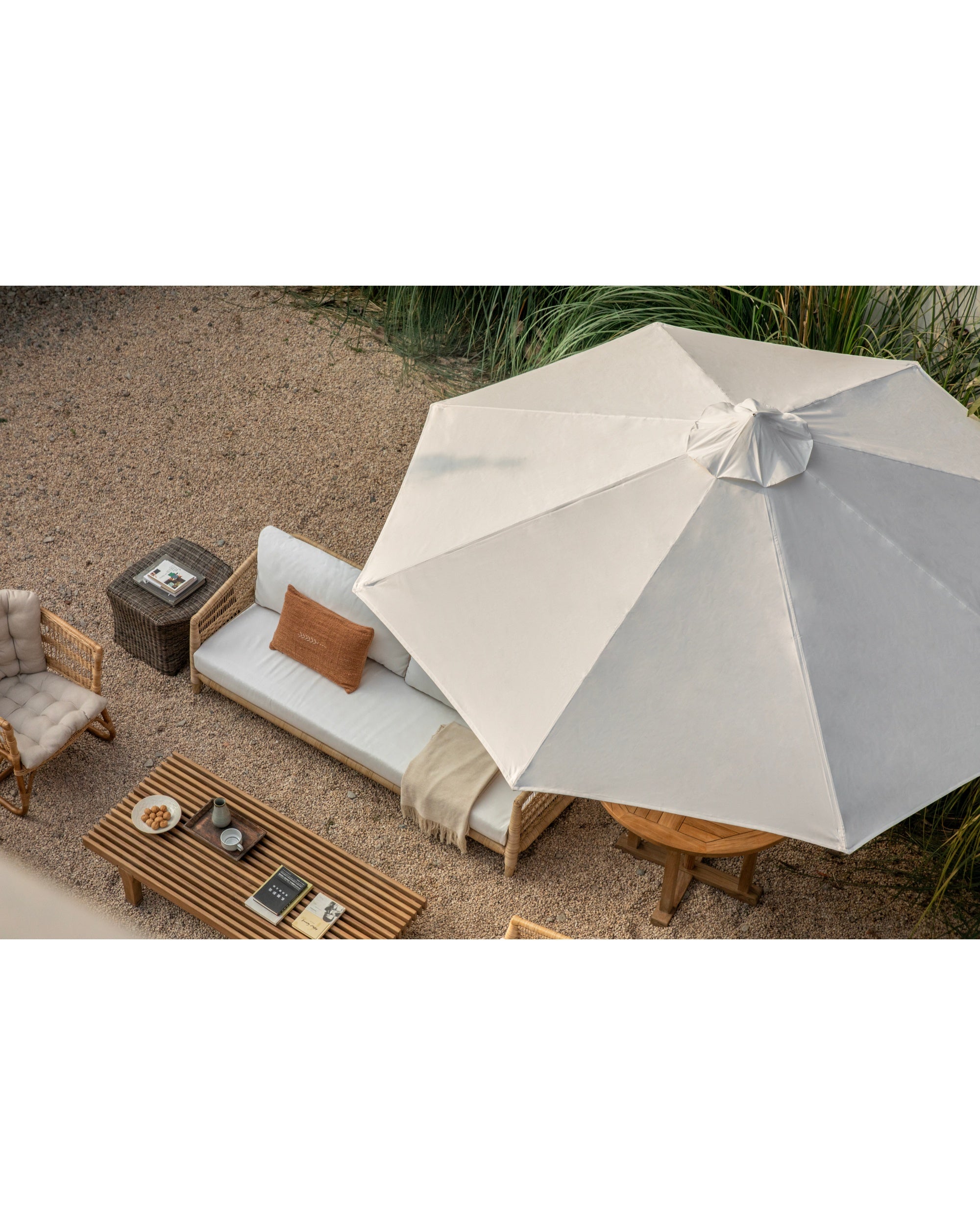 Outdoor teak patio table and umbrella set with lounge seating.