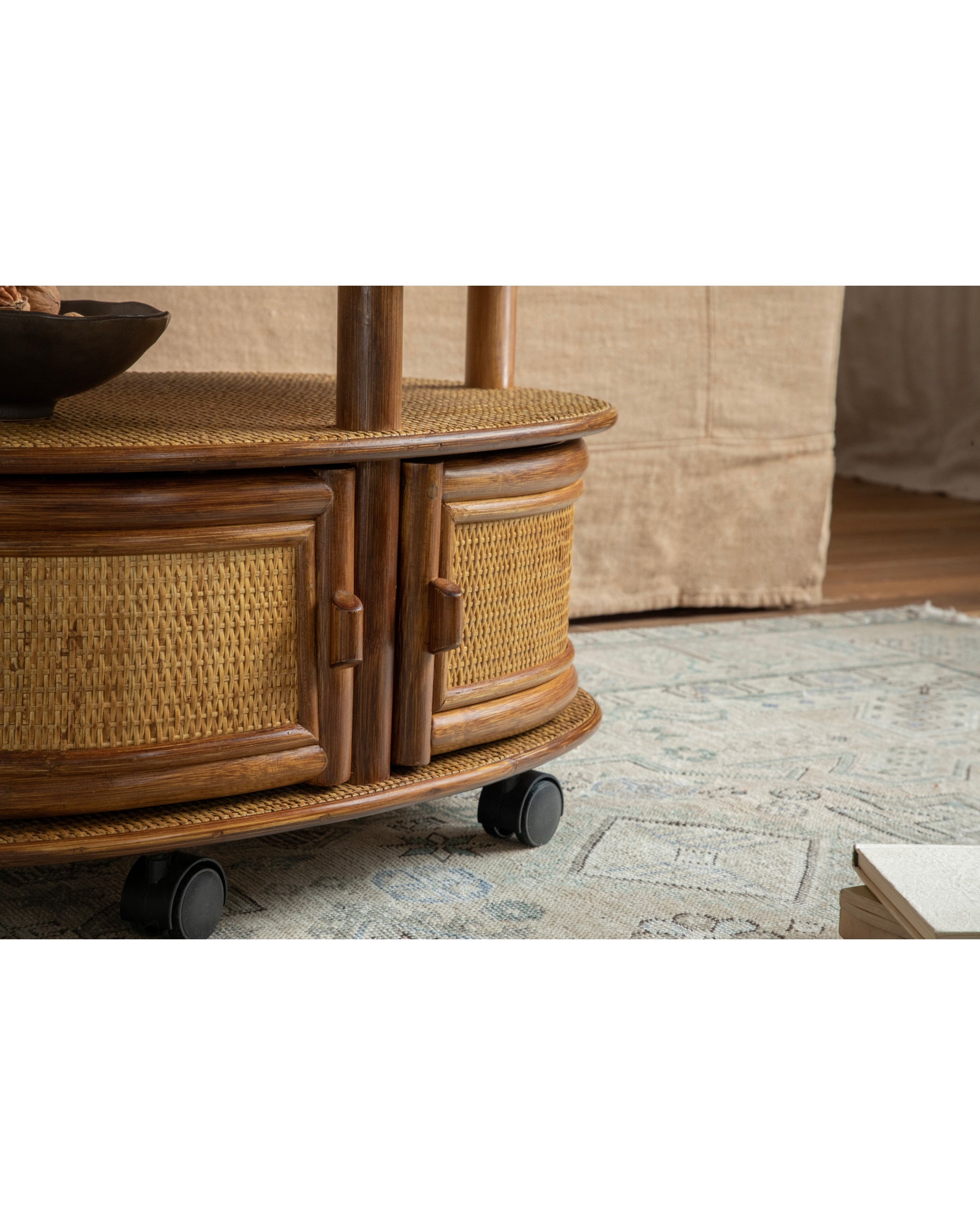 Noa Rattan Wheeled Table with natural Manau cane weave and rolling casters.