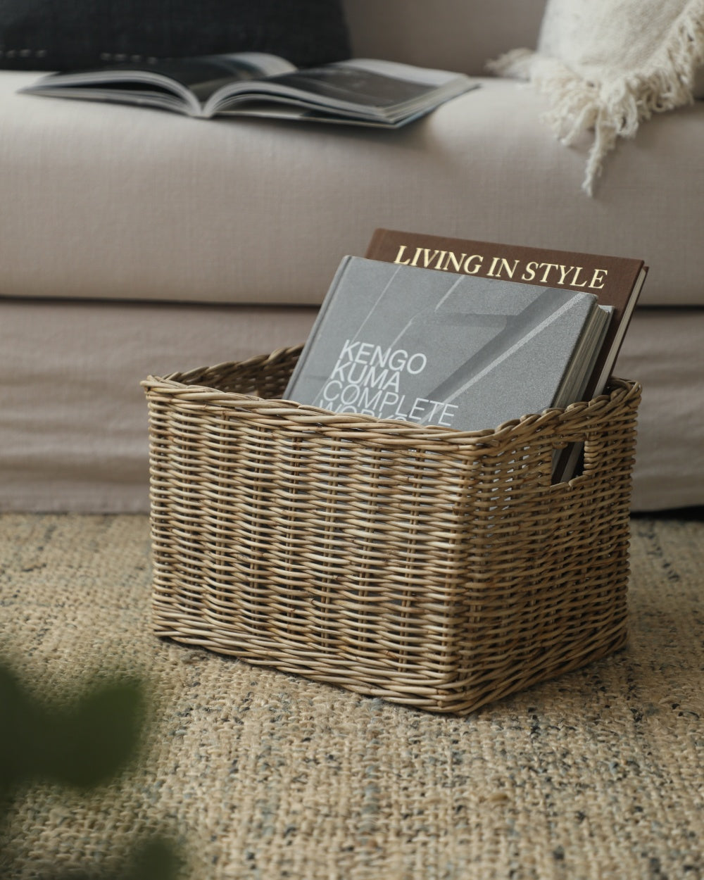 Natural woven Loma storage basket holding books on a neutral living room rug