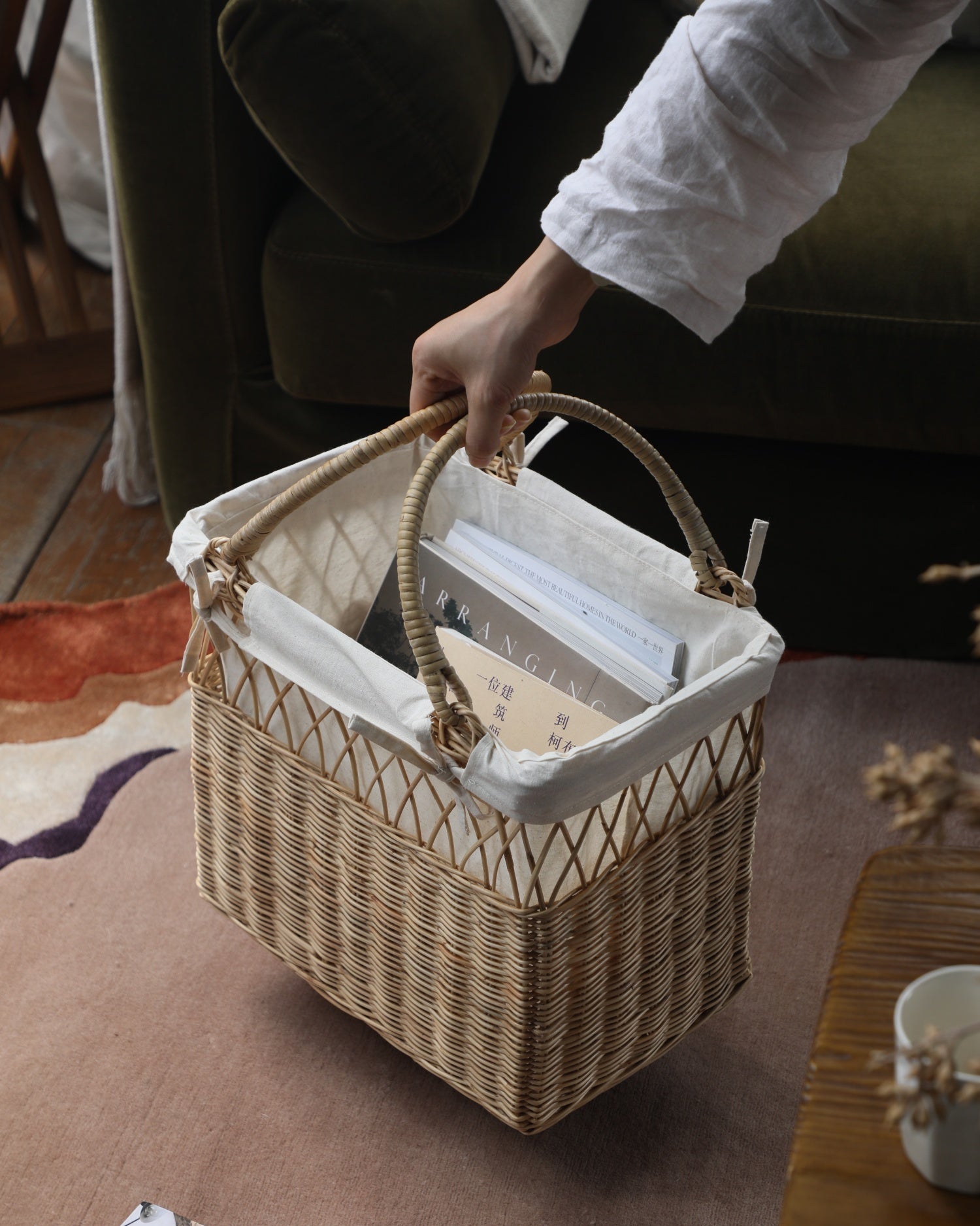 Lina woven rattan storage basket with handles and white cotton lining, holding books.