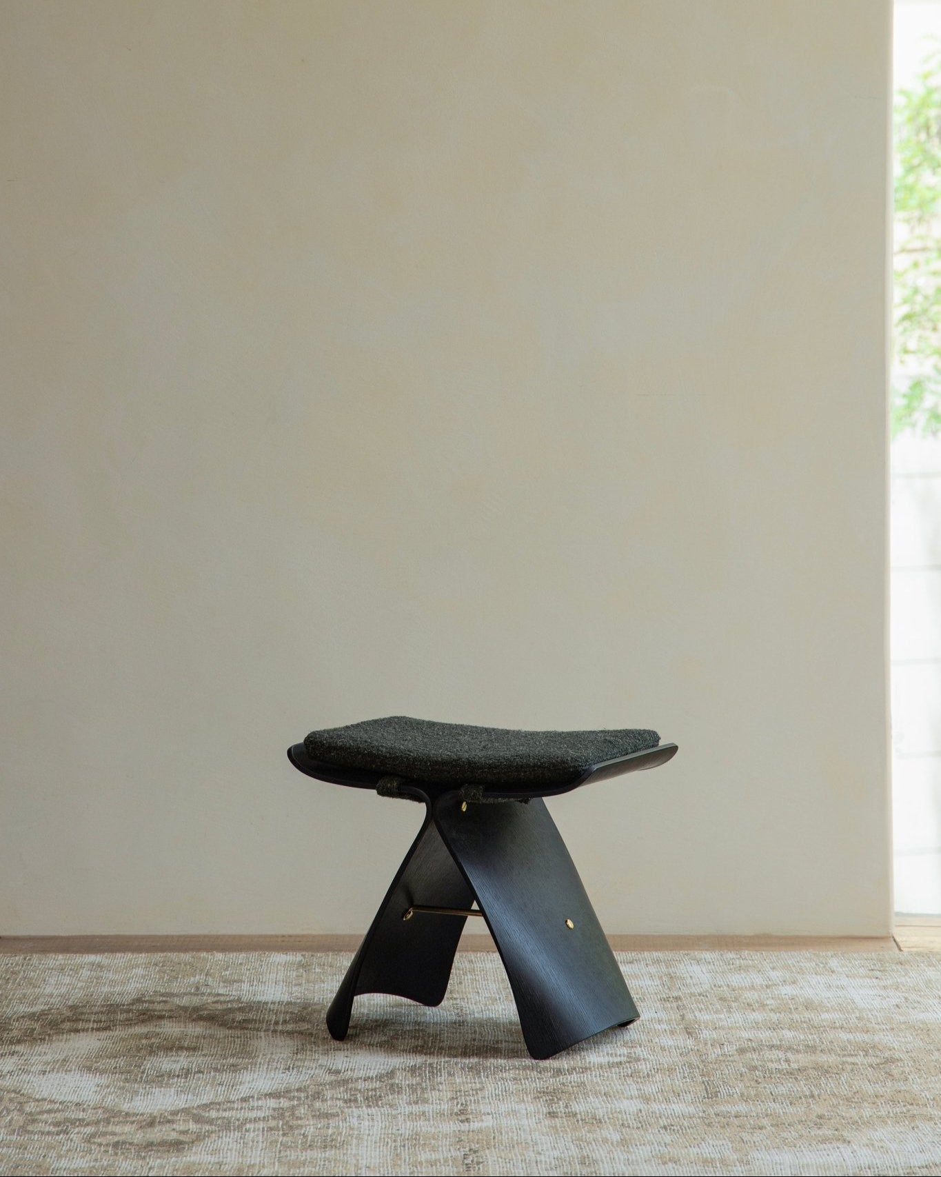 Butterfly Stool in carbonized black finish with dark gray cushion, classic design, modern interior
