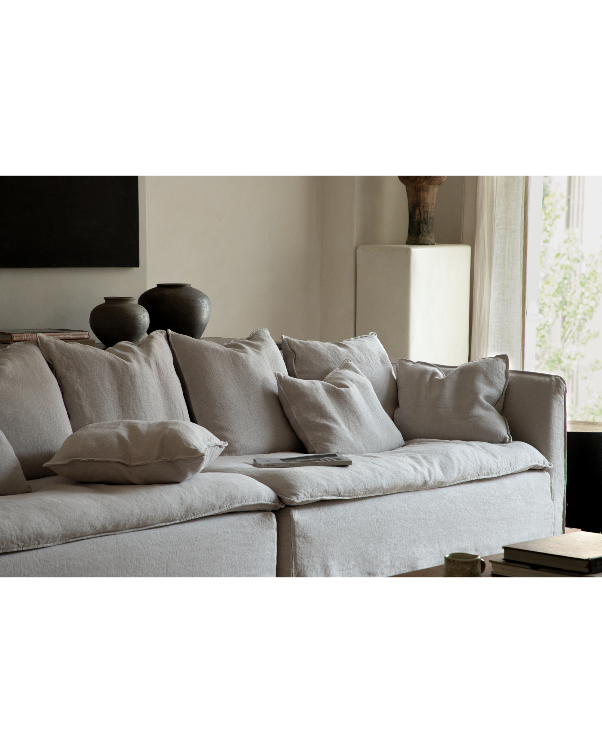 Camille sectional sofa in light neutral linen, featuring deep cushions and plush throw pillows.