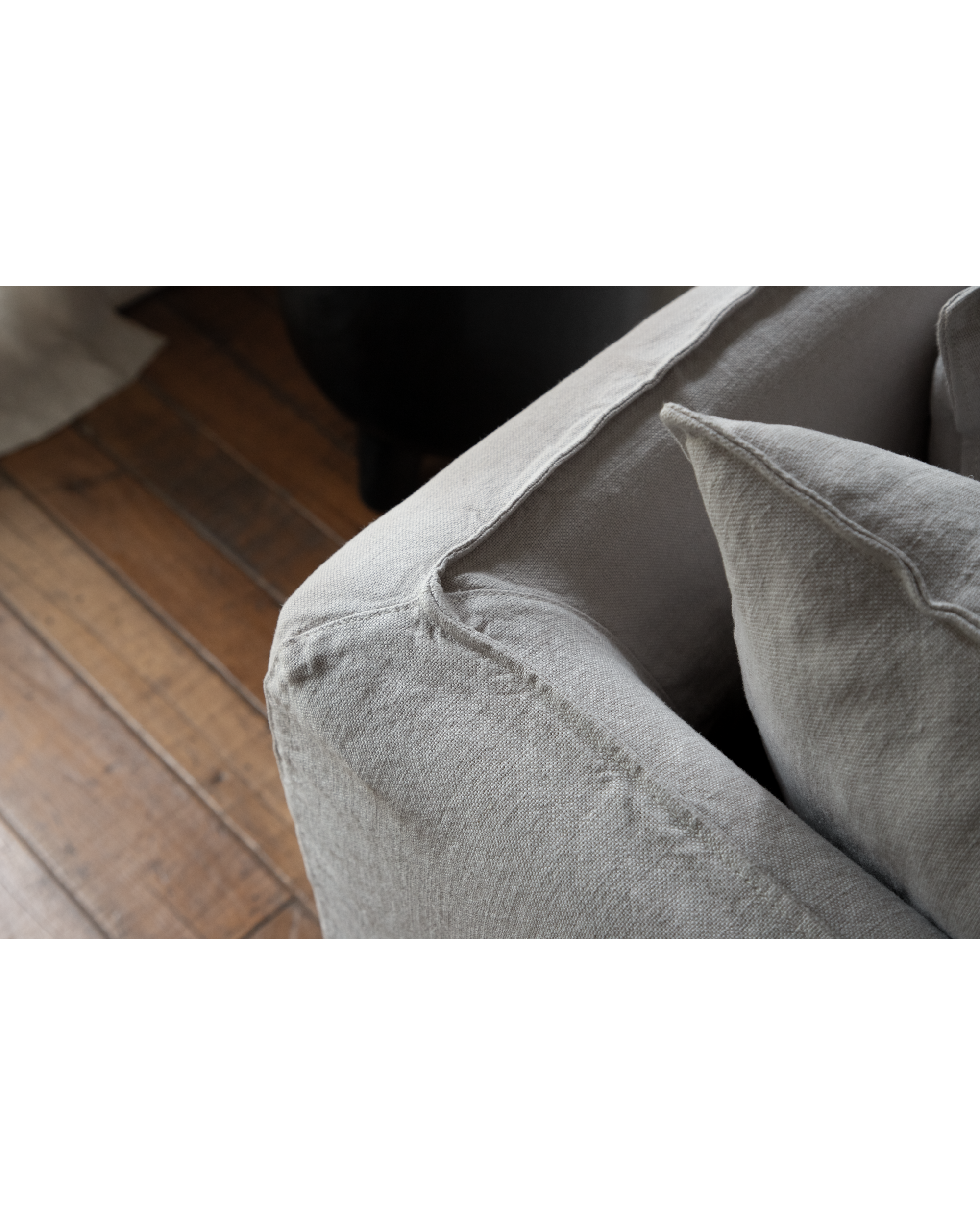 Close-up of Camille Sectional Sofa armrest and cushion in textured light grey linen fabric, showing weave and stitching.