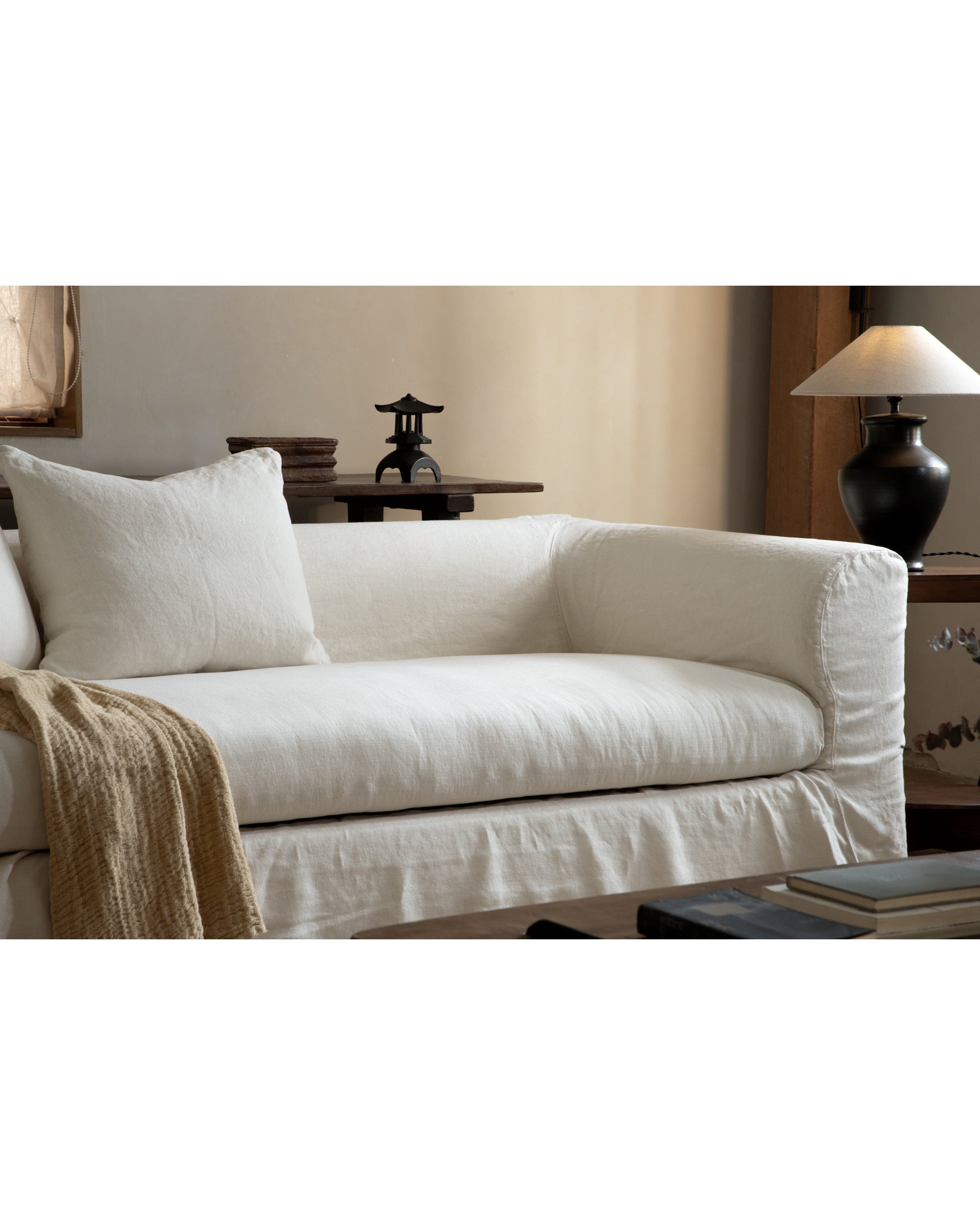 Charlotte Sofa in off-white woven linen, featuring a relaxed slipcover and cozy throw.
