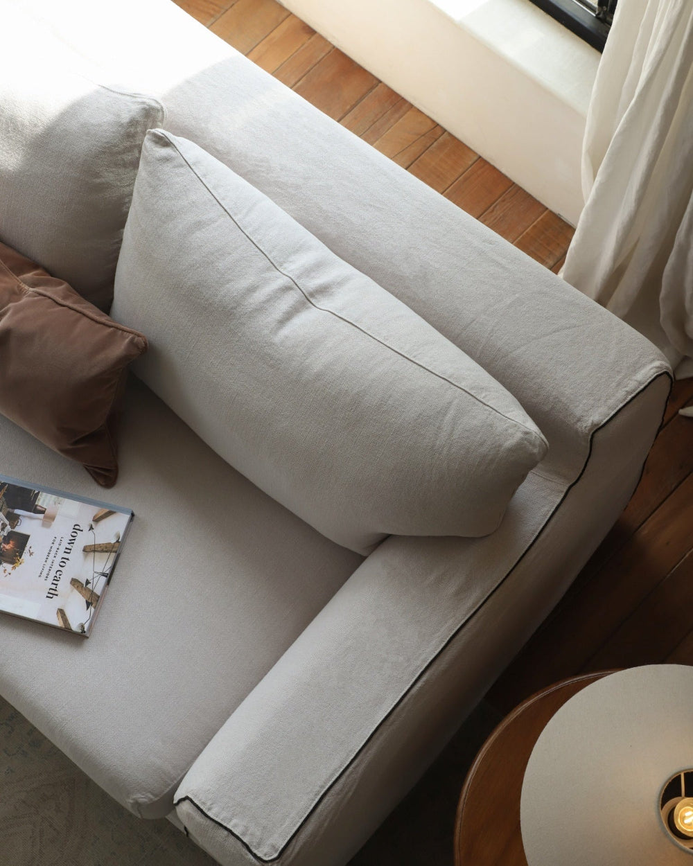 Noa Sectional Sofa in light Belgian linen with plush cushions and elegant black piping details.