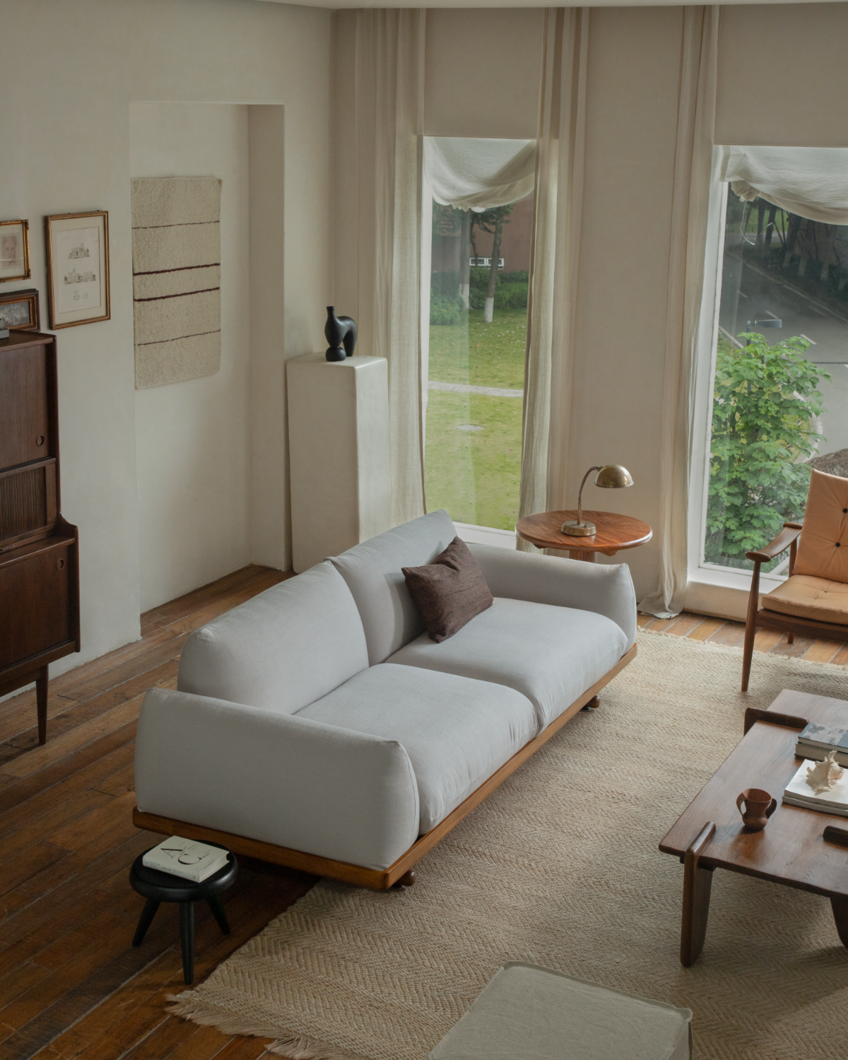 Adrian Sofa in light linen upholstery with teak wood base in a warm modern living room