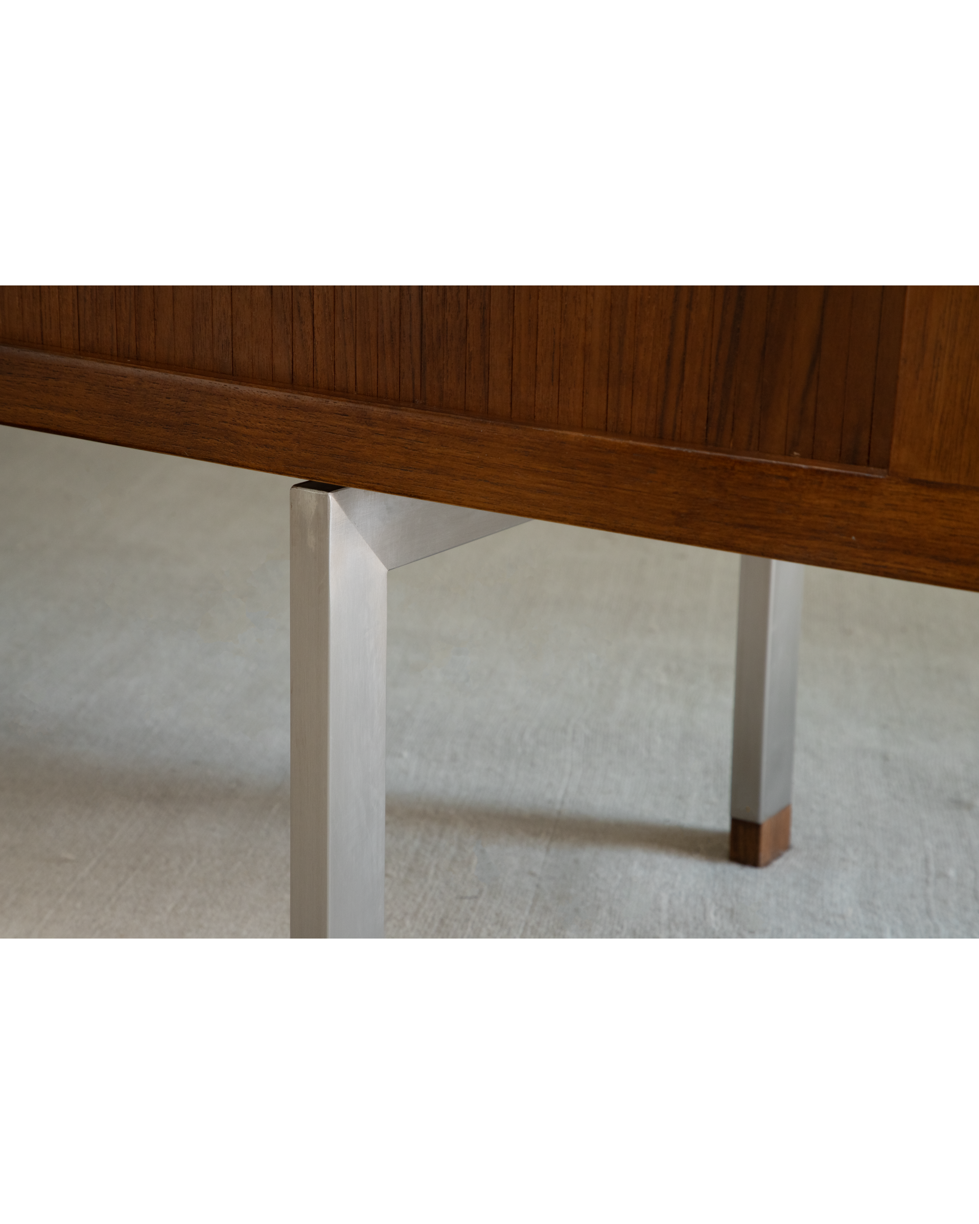Close-up of Martin Credenza: Teak wood roller shutter detail and angular stainless steel legs.
