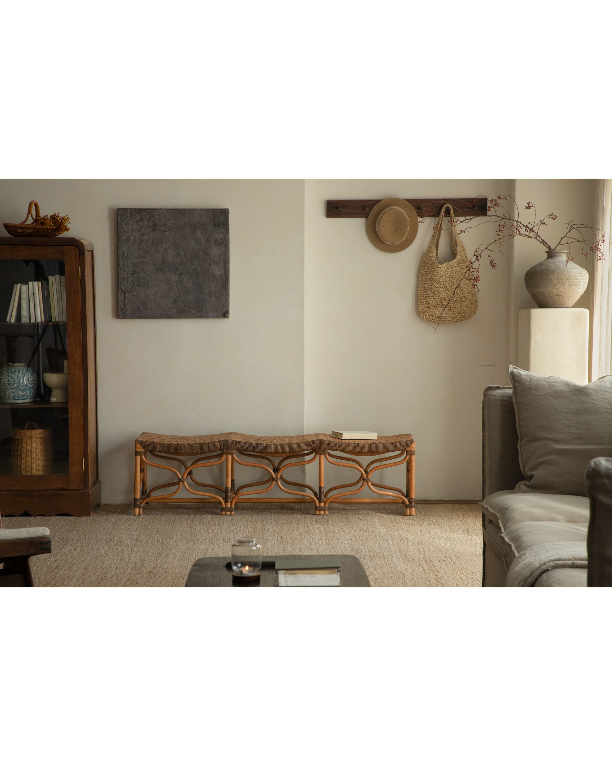 Melange rattan bench with wave-shaped seat and openwork legs in a warm living room