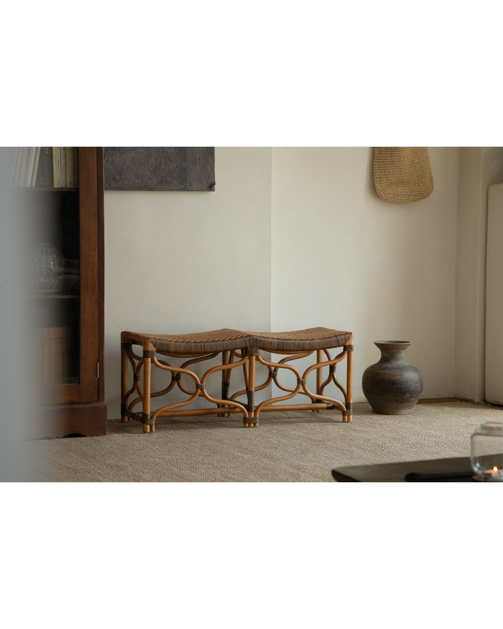 Rattan Melange bench with curved woven seat and openwork legs in a calm interior