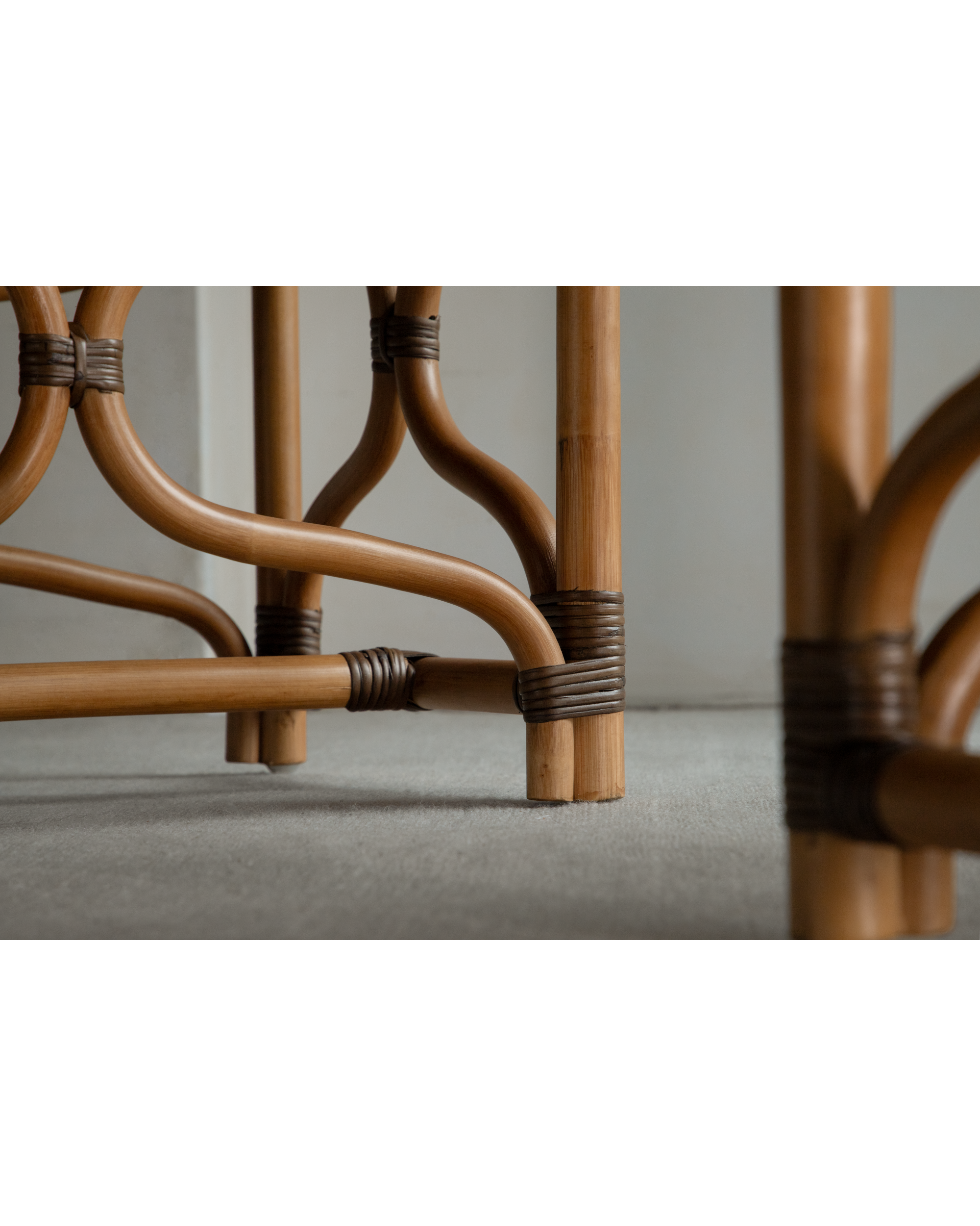 Close-up of Melange Bench curved rattan frame with wrapped joints and tapered legs