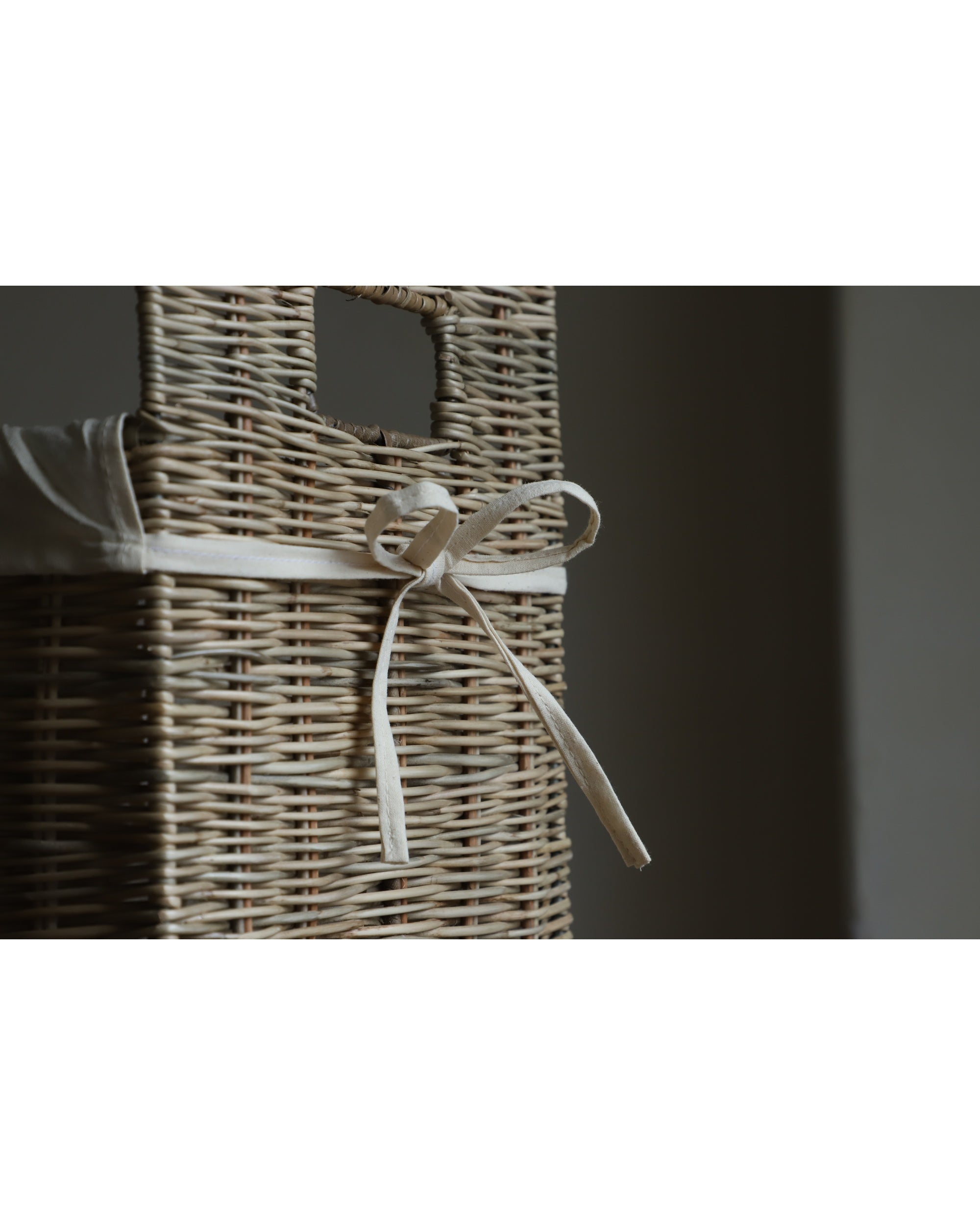 Elara woven rattan storage basket with cream ribbon tie and cotton lining.