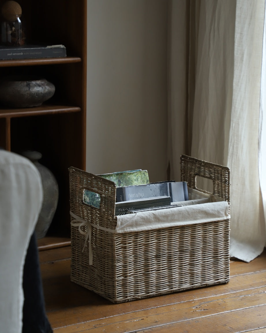 Elara natural rattan storage basket with handles and cotton lining, organizing books.